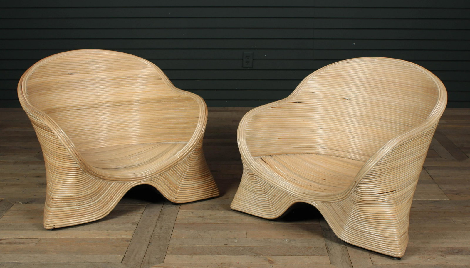 Pencil Reed Lounge Chairs: Pair of Stylish Pencil Reed Lounge Chairs having a barrel back and sweeping arm over a shaped base. Size: 25.5" H x 29" W x 24" D.