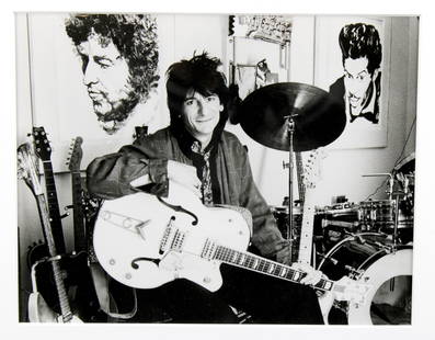 Ron Wood Portrait in Studio: Ron Wood. A man in his studio with his guitars and his artwork. Ronnie flanked by his own drawings: Bob Dylan and Chuck Berry. Ca. 1991 Original vintage silver gelatin print. (RS1146) Sight size: 7.25