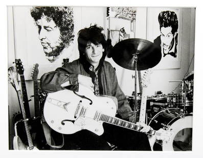 Ron Wood Portrait in Studio: Ron Wood. A man in his studio with his guitars and his artwork. Ronnie flanked by his own drawings: Bob Dylan and Chuck Berry. Ca. 1991 Original vintage silver gelatin print. (RS1146) Sight size: 