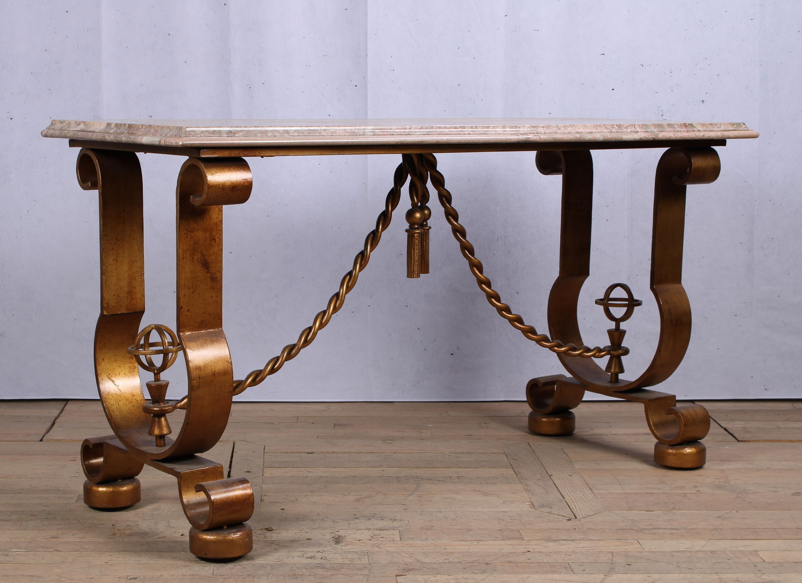 Andre Arbus Style Console Table: A good Andre Arbus style gilt decorated console table having a marble top supported on urn shaped base with twist form stretcher and drop tassels. Size: 33.5"H x 61"W x 25"D