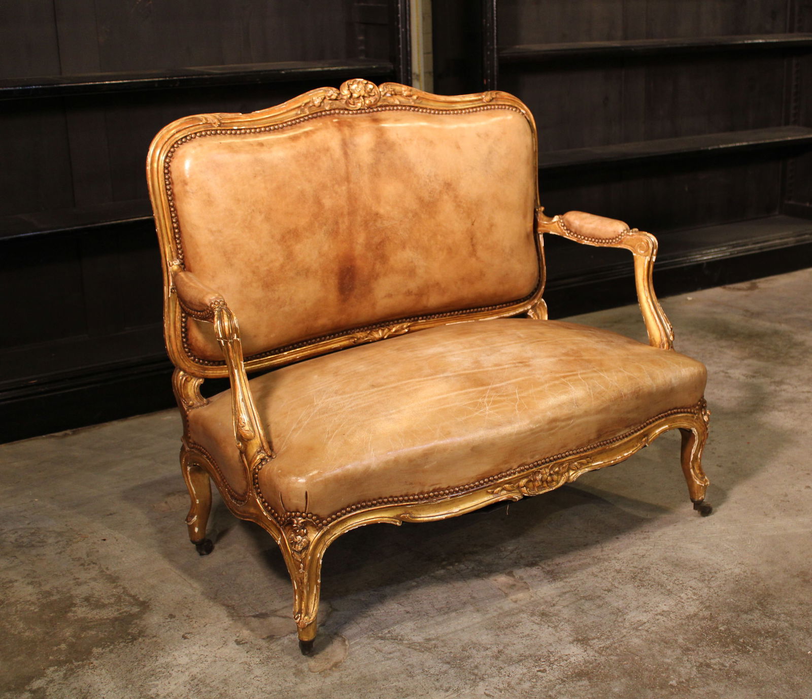 Louis XV Leather Canape: A French Louis XV style gilt wood carved canape having a leather upholstered back and seat raised on cabriole legs with casters. Size: 38.5"H x42"W x22"D seat height 16". Circa: 1890 List Price: $4700