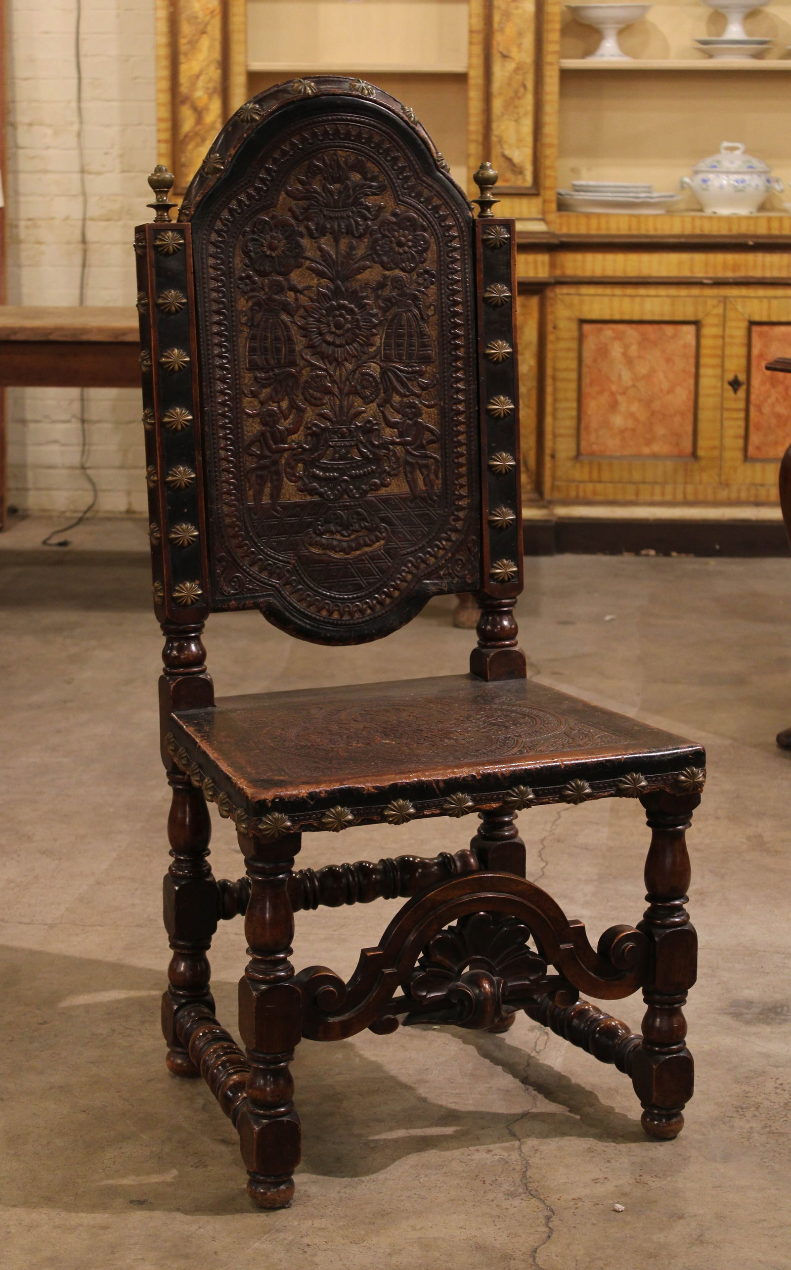 Italian Embossed Leather Armchair: Italian Embossed Leather Armchair, floral motif with maidens, oversized start shaped nail head trim and heavily carved cross brace. Size: 49.5"T x 22.5"W x 18.5"D , 19 seat Circa: 1870 List Price: $33