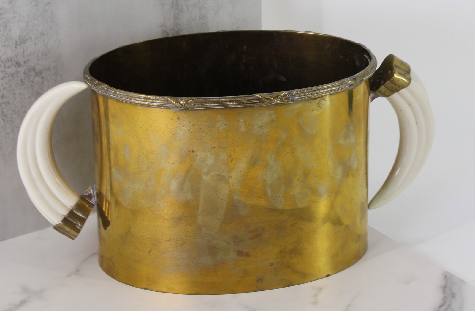 Brass Ice Bucket with Tusk Handles: Brass ice bucket with faux tusk handles, small crack in the seam on the bottom. Size: 7.5"T x 14"L x 7"D