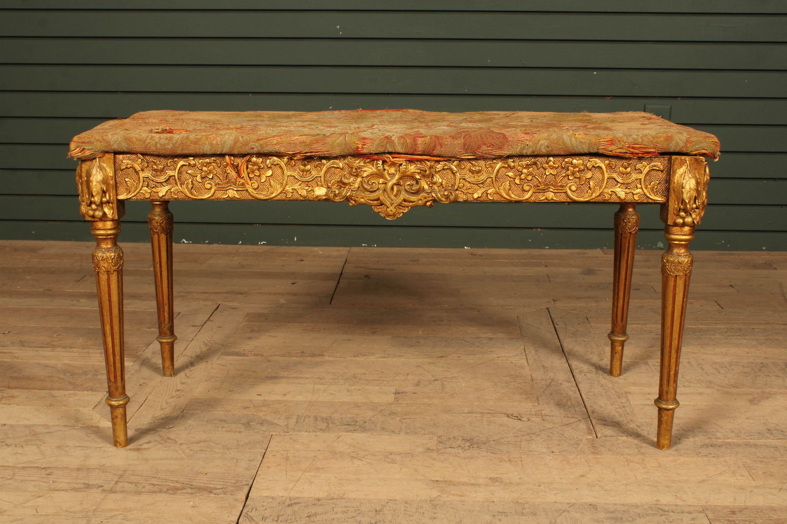 Louis XVI Gilt Upholstered Bench: French Louis XVI gilt wood bench, heavily carved frame with turned legs. Upholstery has little to no foam and brocade fabric is very worn. As-Is. Size: 19"H x 35.5"W x 15.5"D