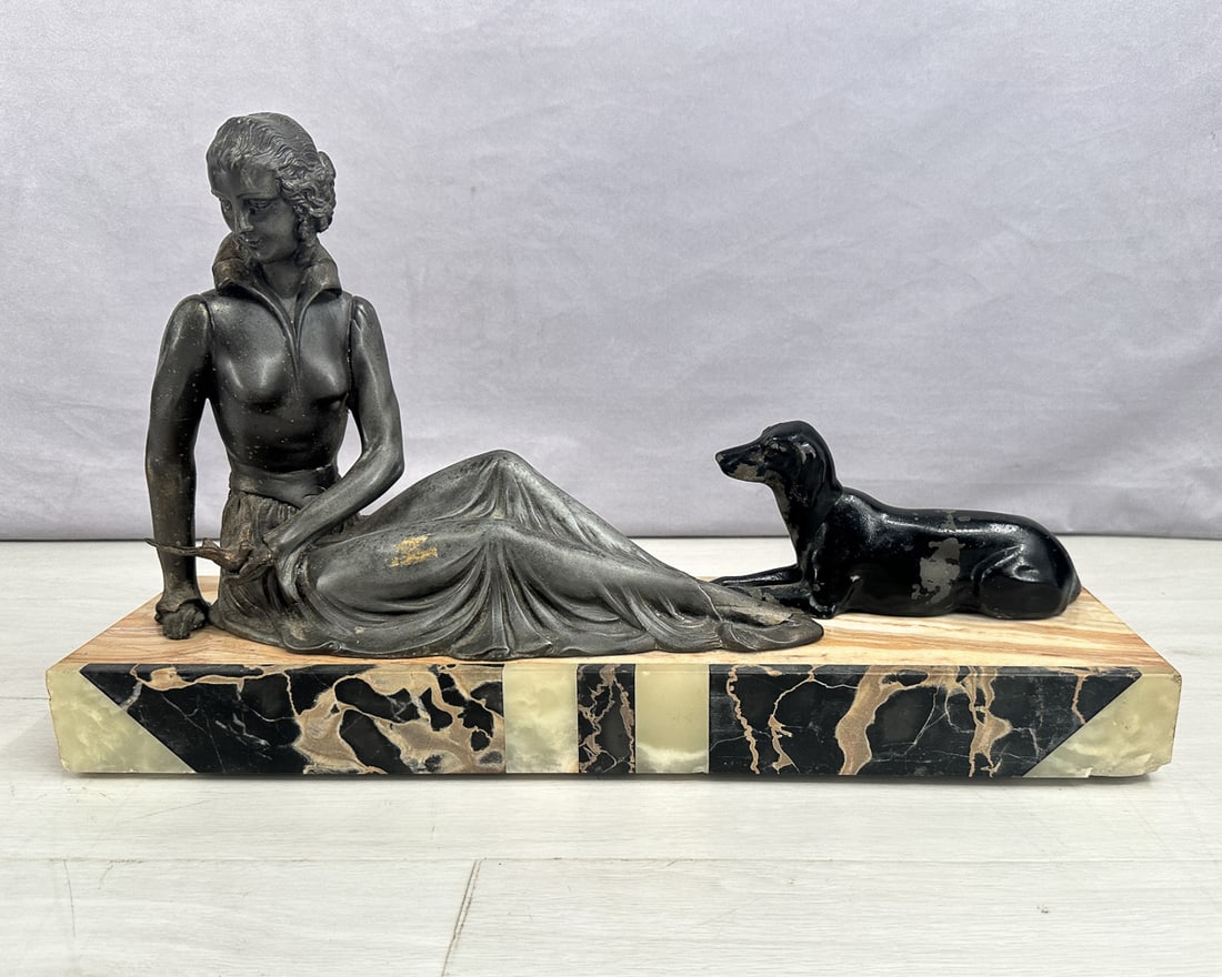 Art Nouveau Woman & Dog On Plinth: Art Nouveau mantle sculpture of a seated women with a bird in her hand and dog. Both pieces are cast iron, sitting on a mosaic marble base. Figures are no longer attached to the base but the holes for