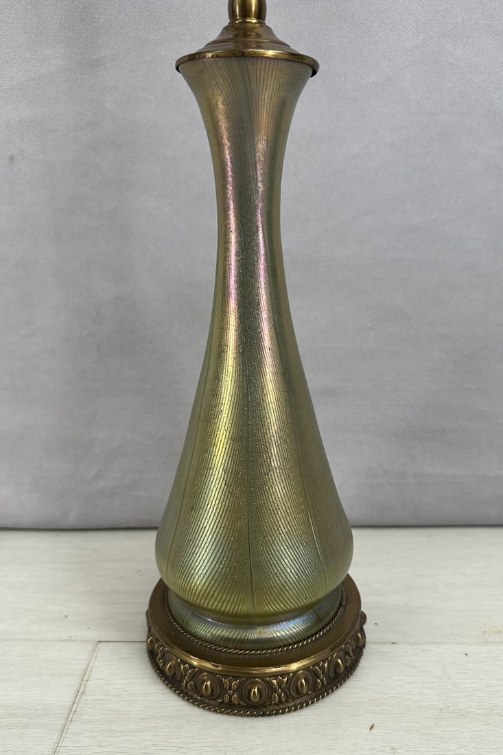 Loetz Attributed Iridescent Glass Lamp: Loetz attributed glass lamp, features a favrile style iridescence that photos don't truly capture. Brass base and fixture. 2 bulbs with independent pull cords. Untested. Size: 25"T x 5" diameter base