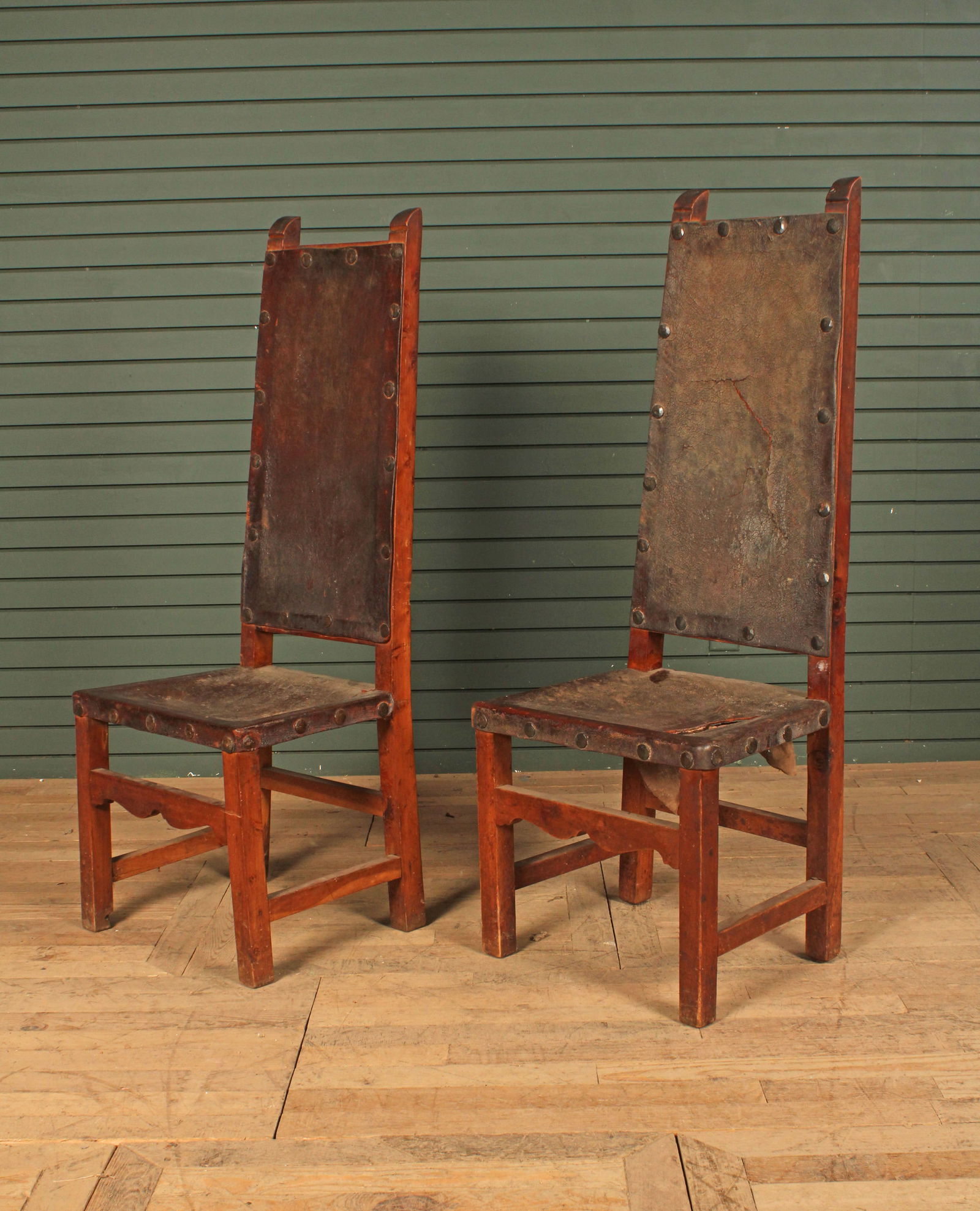 Two Spanish revival high back leather chairs,  wooden frames, bold nail head trim. Tear to one  seat (1 of 8)