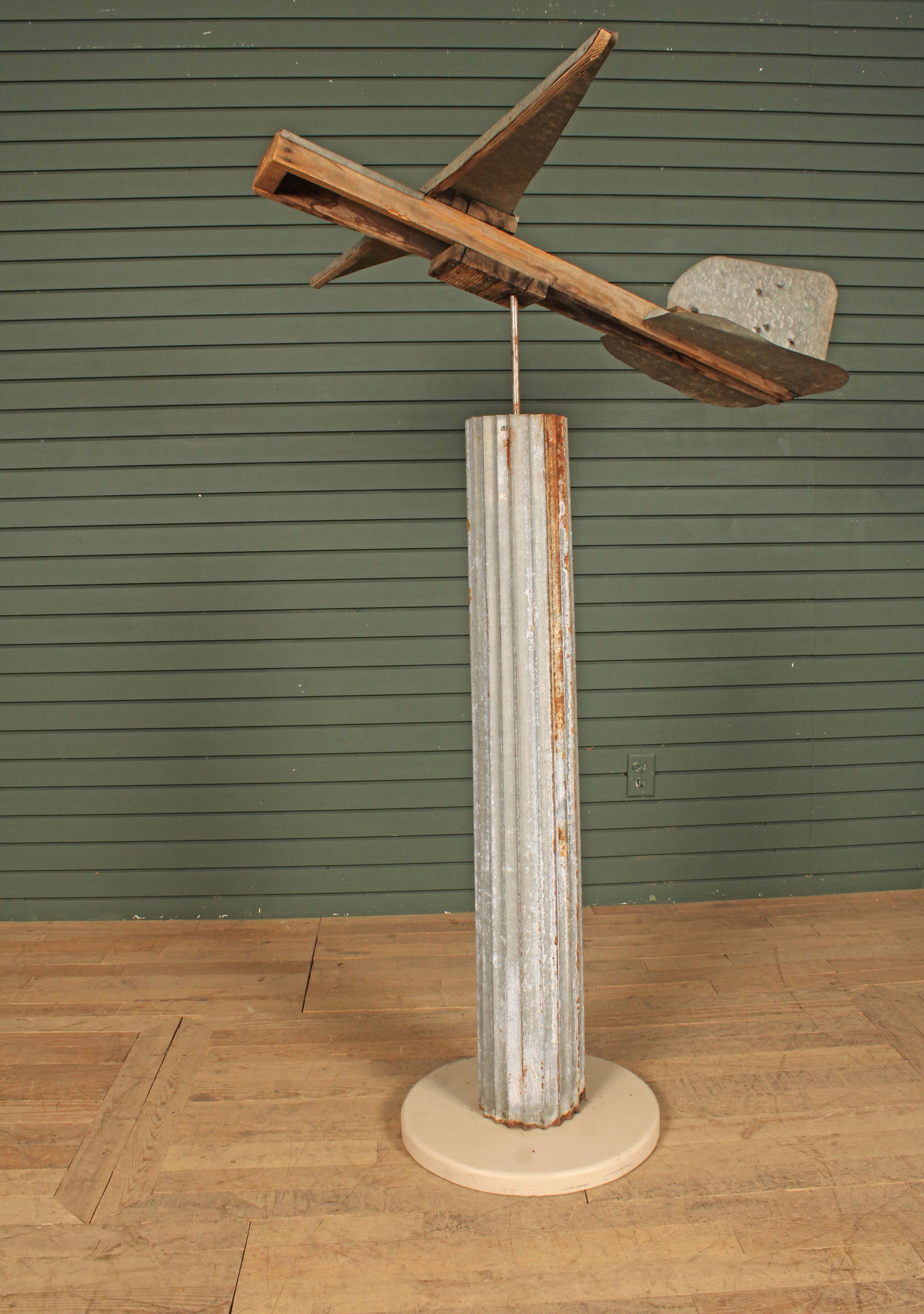 Plane Weather Vane, Folk Art Whirlygig: Folk art sculptural weather vane, corrugated tin pedestal with metal and wood plane. Size: column 59"H x 20"Dia. plane 11"H x 42"W x 45"D