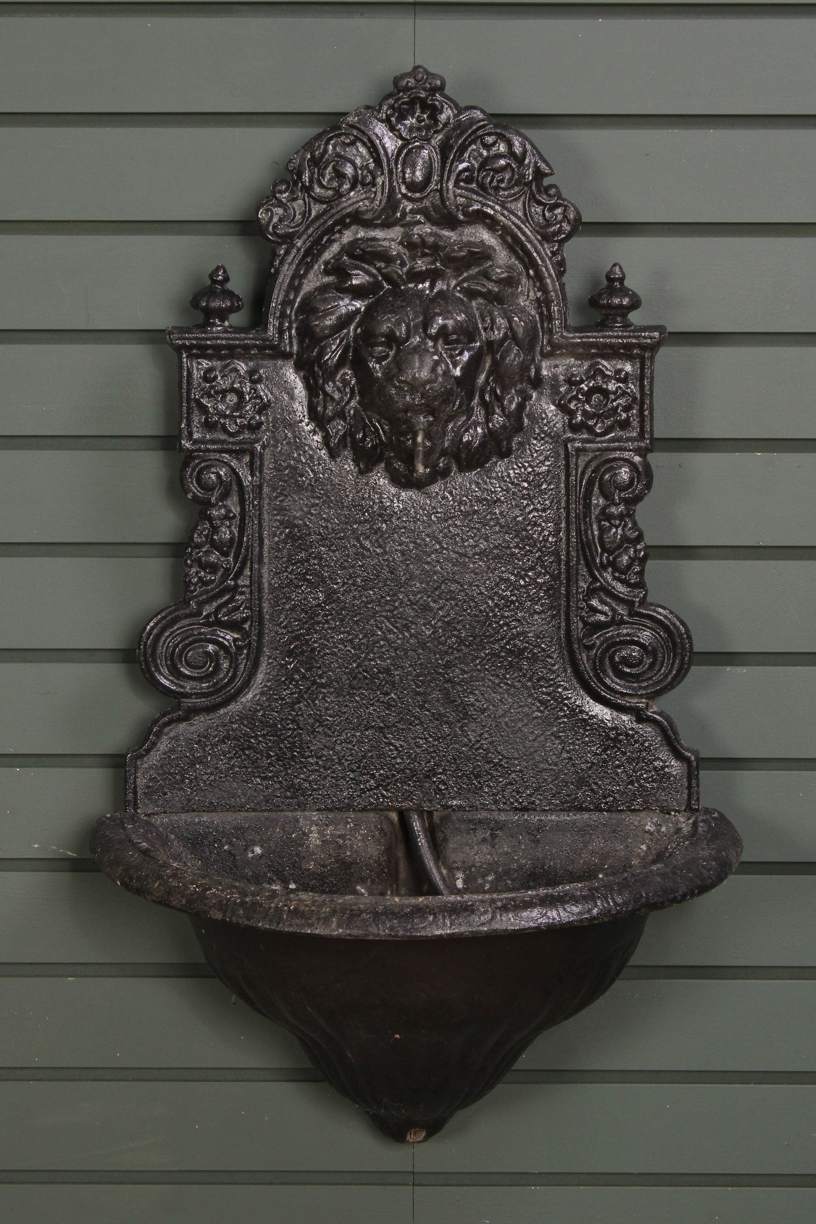 Lion Head Wall Fountain, Lavabo: Composite lion head lavabo, black paint, scroll work, patina and wear throughout. Light weight. Size: 31"T x 19"L x 12"D