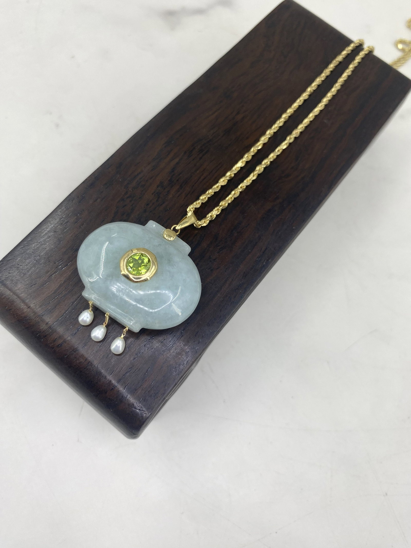 Jade Lantern Pendant on 14K Gold Chain: Carved celadon green jade lantern form pendant with 14K gold accents, peridot and fresh water pearls. 14K gold rope chain. Stand in not included. Size: 20" chain, 1.5"T x 1.5"W pendant, 18.2 g