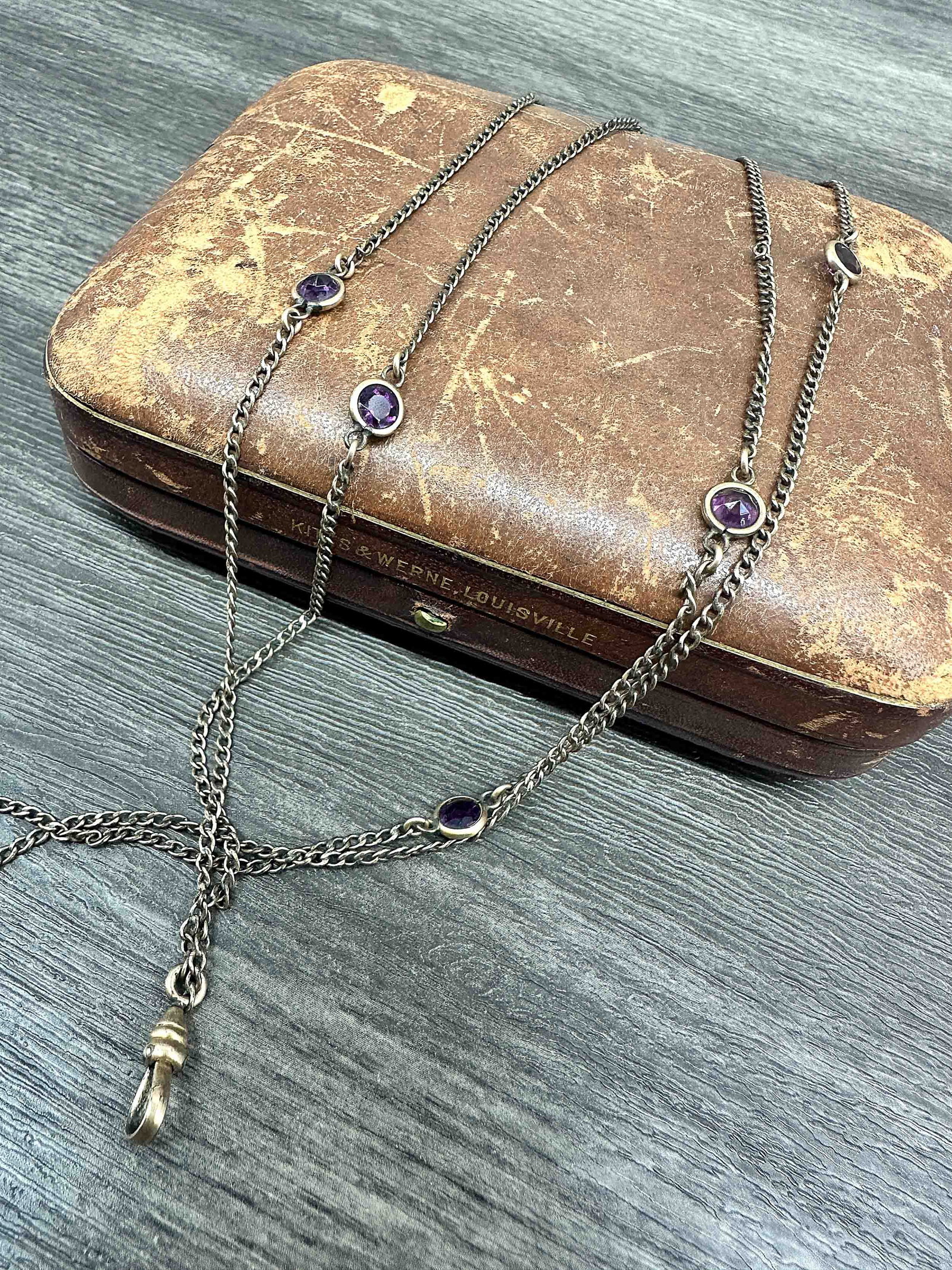 J. Lynne Guard Chain with Amethyst: Antique guard chain, pocket watch chain. Would be considered an opera length necklace, has 8 round cut amethysts in a bezel setting spaced throughout the chain. Stamped on dog clip, J Lynne & Co. Jewe
