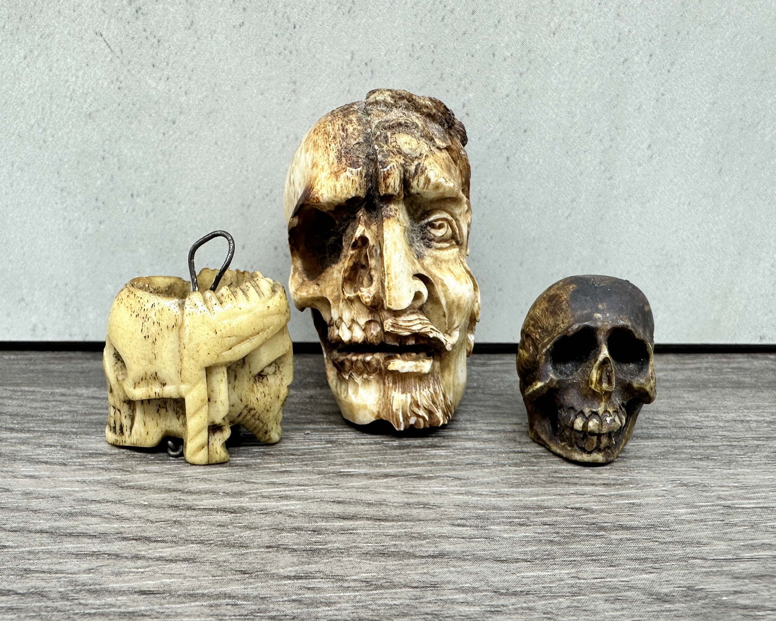 Carved Bone Skull Group, Janus: 3 miniature carved bone memento mori skulls. One is drilled to wear as a pendent and has a double face with Jesus on one side and a skull on the other. The smallest is intricately carved with great pa