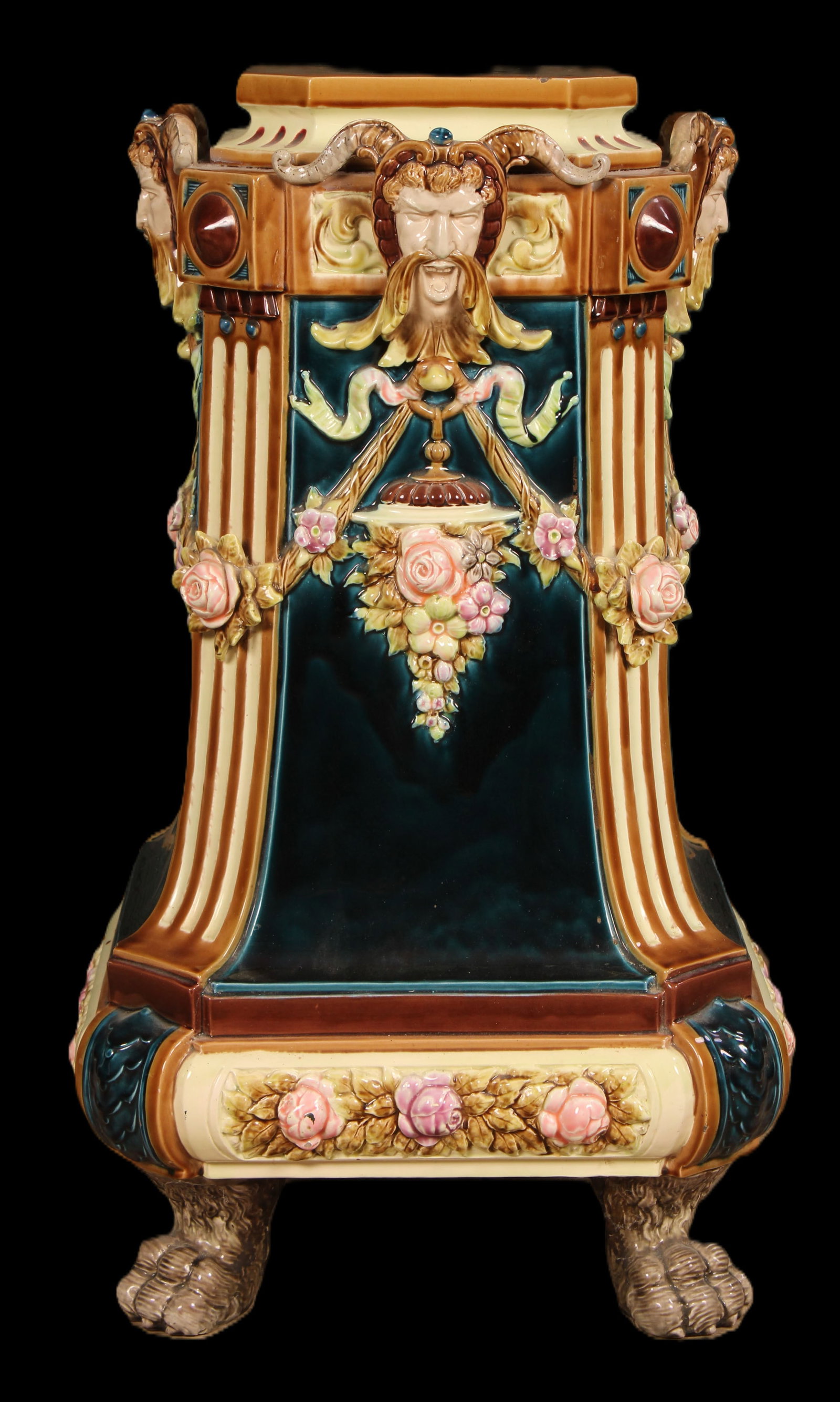 Majolica Pedestal, Ram Horns, Paw Feet: A majolica style pedestal having rams horn decorated masks over floral and ribbon swags all framed by fluted corners resting on paw feet. Size: 31.5"H x 18"W x 18"D
