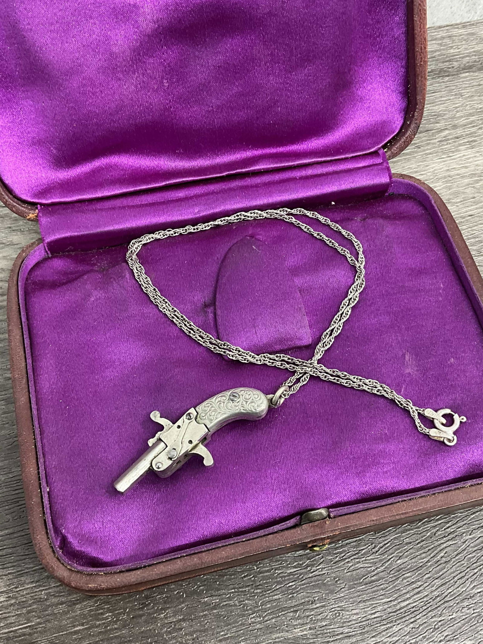 Pinfire Gun Pendant, Austria Berloque: Austrian made berloque style pinfire pistol, 2mm, all nickel, scroll work handle, made into necklace. Hammer moves, barrel opens, trigger moves. Chain sterling silver made in Italy. Early to mid 20th