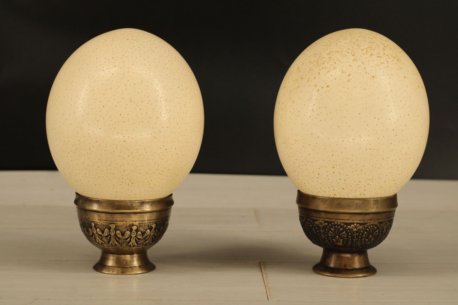 2 Ostrich Eggs on Stands: Pair of Ostrich eggs on brass cup style stands. Size: 8"H x 5"Dia