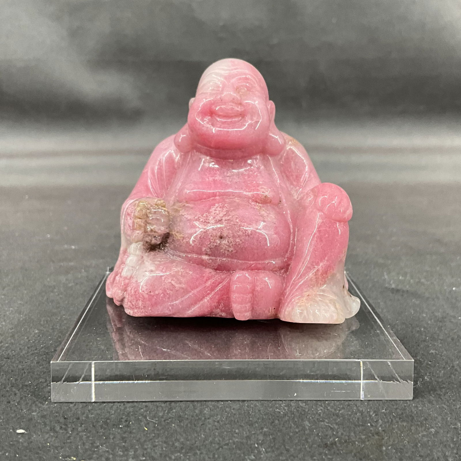 Rhodonite Buddha On Lucite: Carved rhodonite Buddha with tiny green inclusion on head. Comes with lucite stand. Size: 2.75"T x 2.5"W x 1.5"D without stand Provenance: From the lifetime collection of an Oreland, Pennsylvania priv