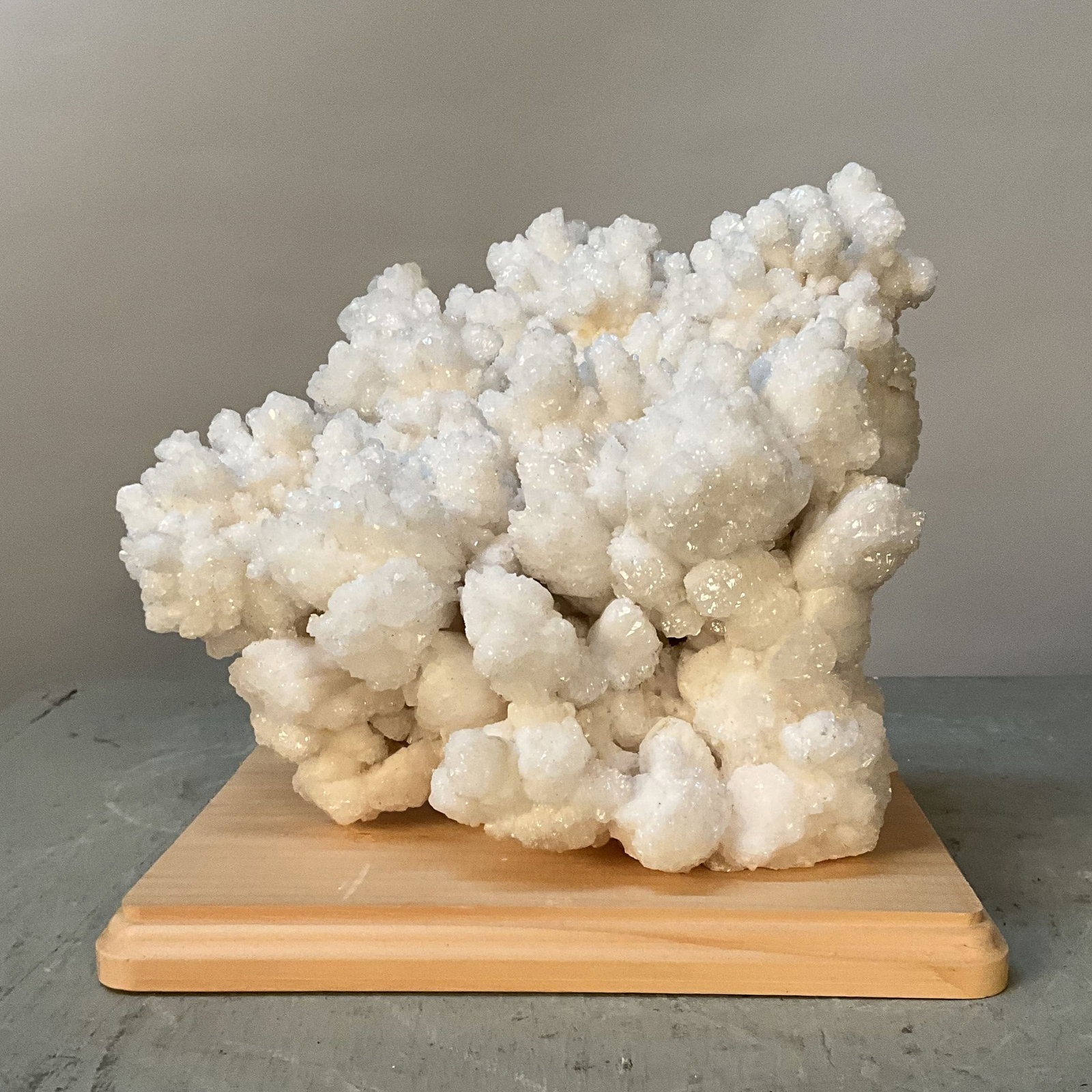 White Aragonite On Wood: Natural form white aragonite (UV reactive) on wood stand, lovely sparkle. Size: 7"T x 8"L x 5.75"D with out stand Provenance: From the lifetime collection of an Orland, Pennsylvania private estate.