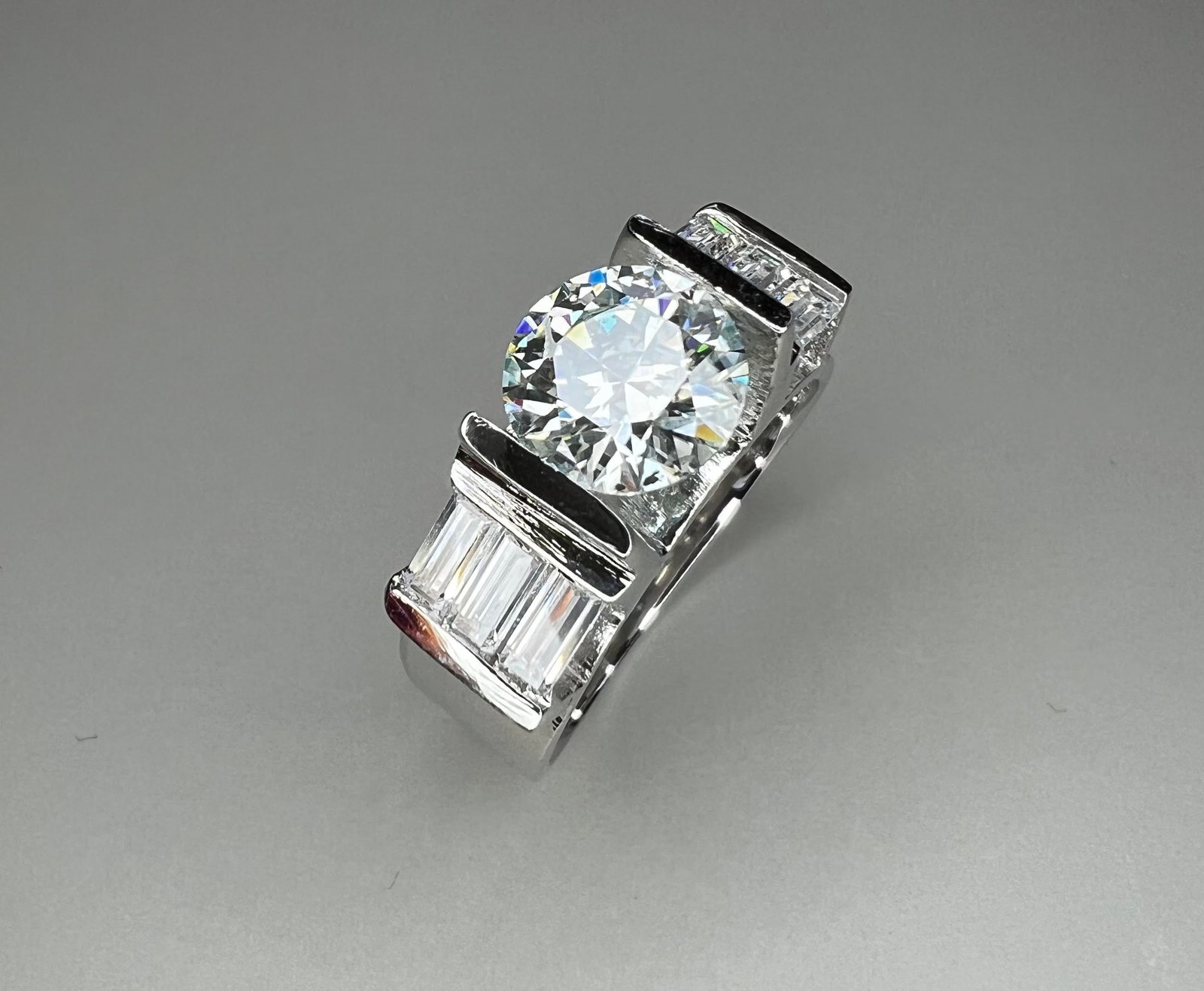 Sparkling 2.5 Ct VVs1 White Fire Moganite Ring: his 2.5 Ct Fire Moissanite is a VVs1 eye clean approx. E-F in color brilliant round cut measuring approx.7 mm. It is mounted in high polished Solid .925 Sterling Silver with 6 sparkling baguette cut a