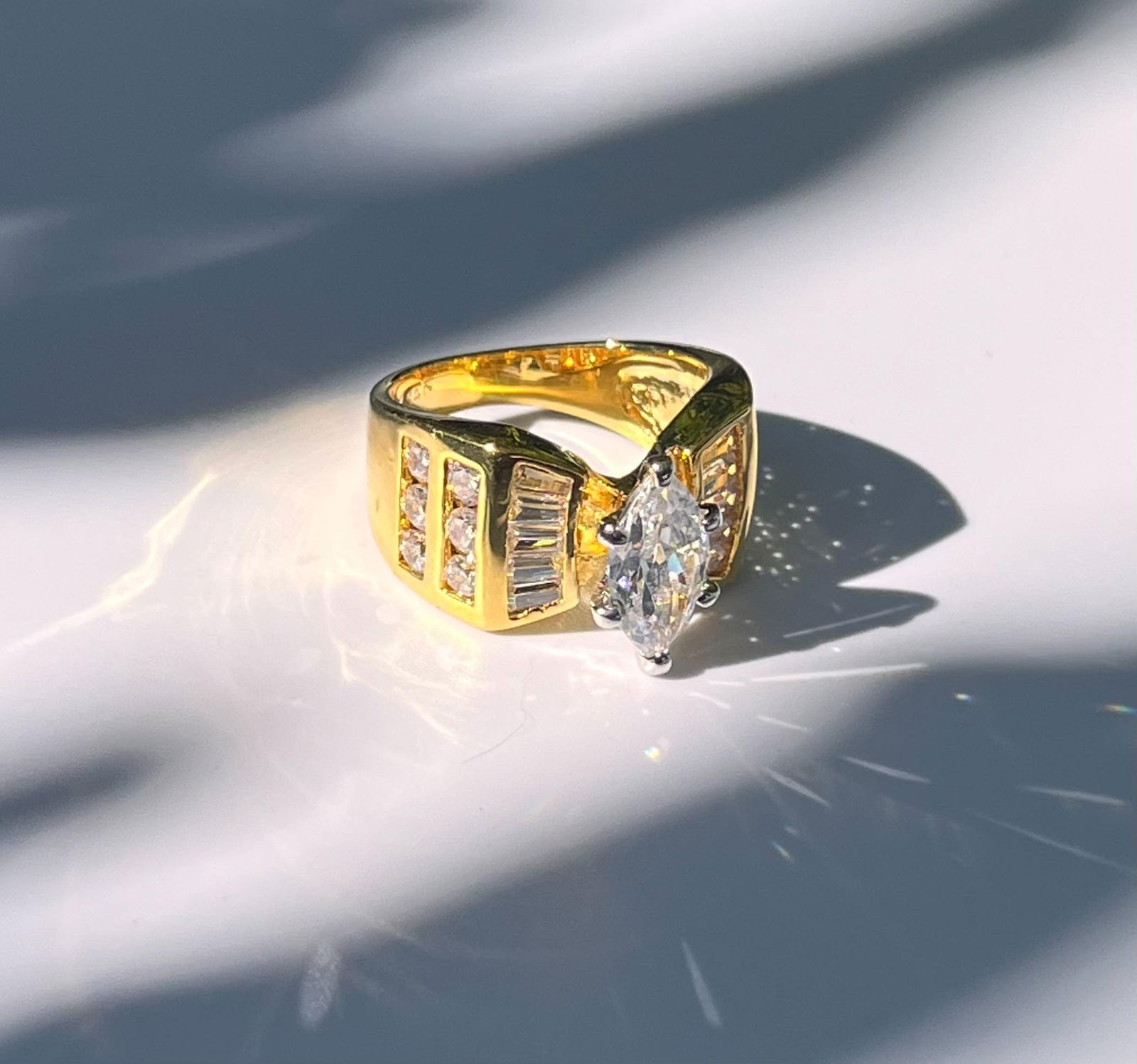 Stunning 14 Kt Gold Plated Simulated Diamond Ring: Sparkling 14 Kt Gold Plate 3.35 Ct Marquis Cut Simulated Diamond Ring. This 3.35 Ct VVs1 Eye Clean Centerstone is complimented by 10 Fancy Baguette Cuts and 12 Brilliant Round Cut Created Diamonds Tot