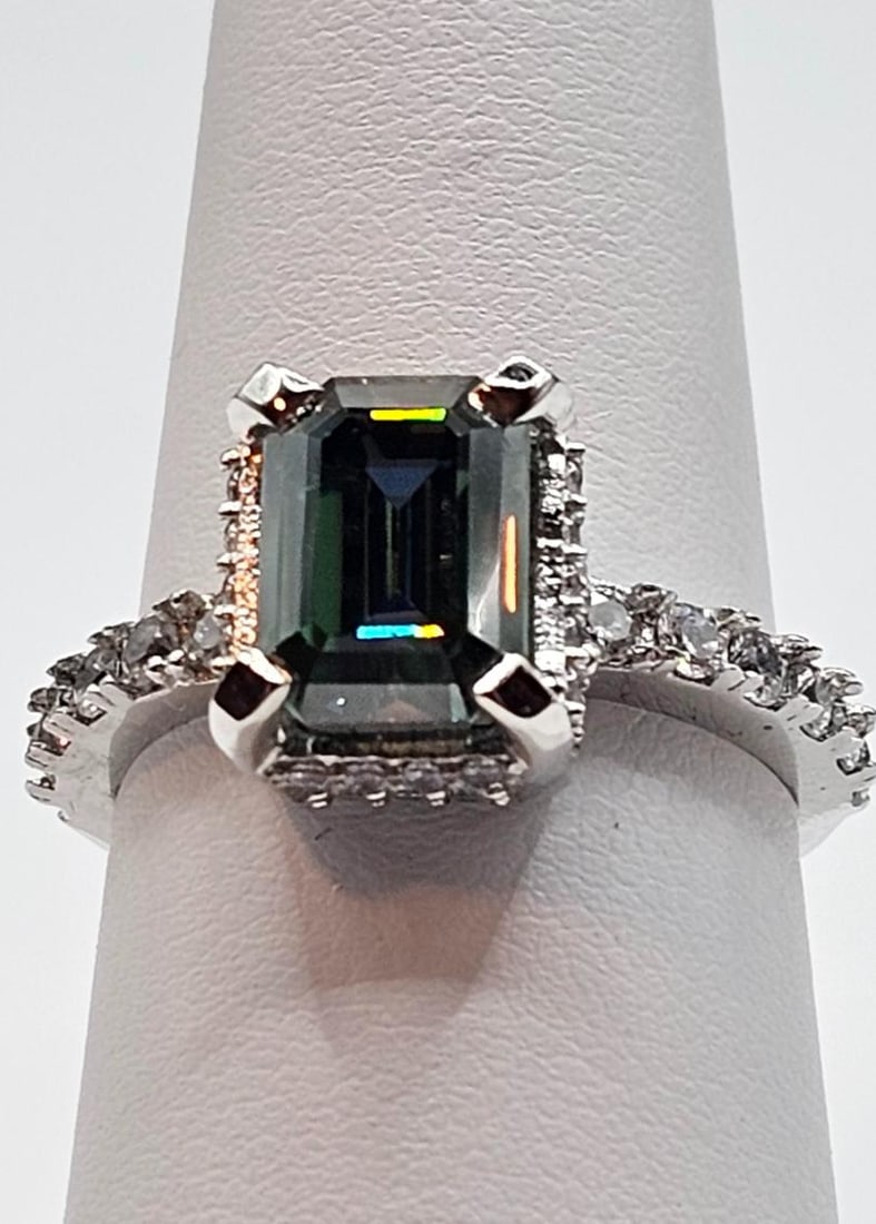 Dazzling 4.5ct VVs1 Deep Emerald Green Fire Moissanite Ring: This Moissanite is a 4.5 Ct Emerald Cut Measuring 9 x 7.5 mm. The Color is Deep Emerald Green. The Clarity is VVs1 . It is mounted in 14 Kt White Gold over solid .925 sterling silver. With a refractiv