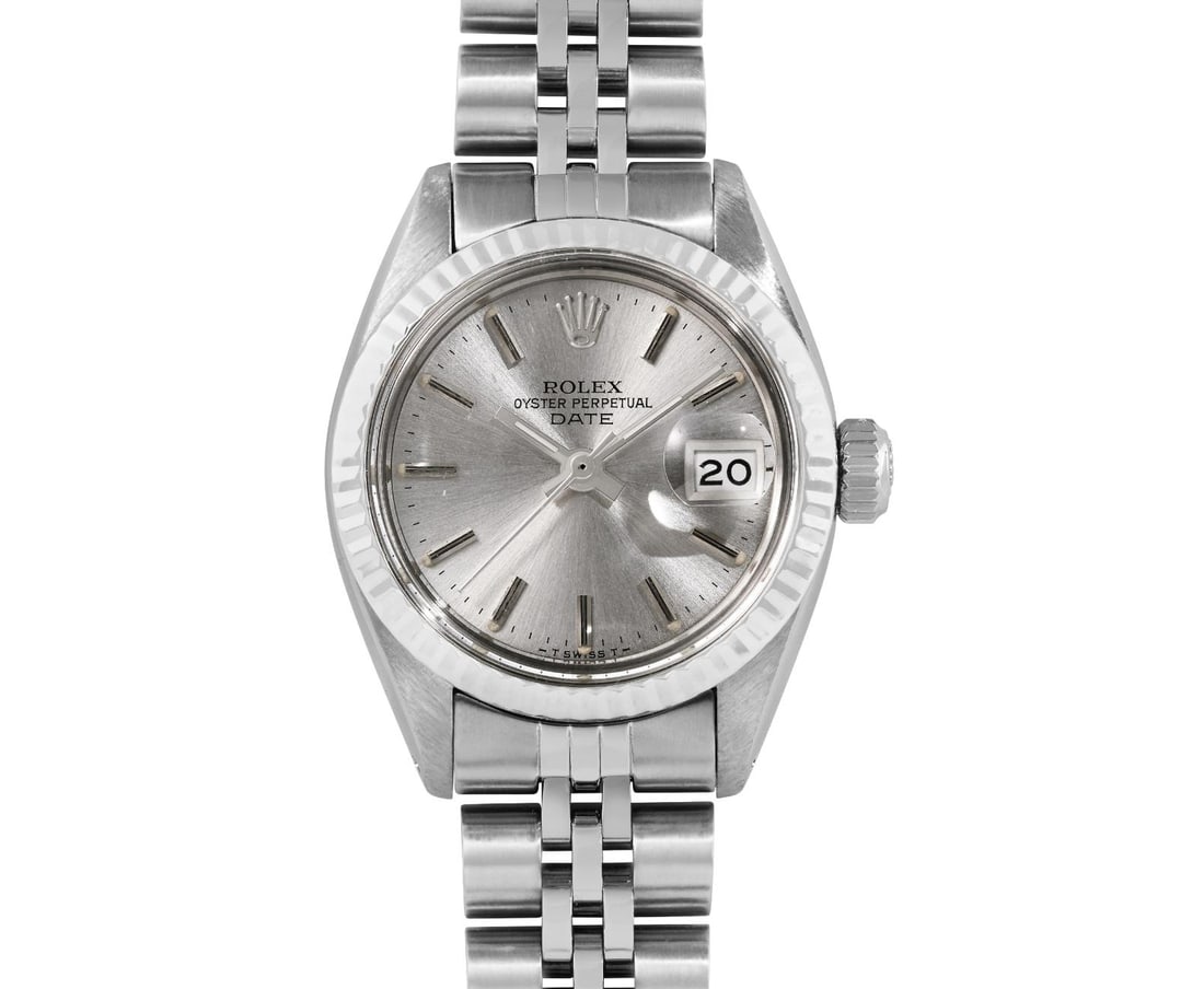Rolex Ladies Stainless Steel 14K Fluted Bezel Date Watch: This Lady Rolex Date watch features a silver dial with index hour markers and a custom plastic crystal, with a magnified date window. The timepiece has Rolex 14K white gold fluted bezel. The Rolex 26m