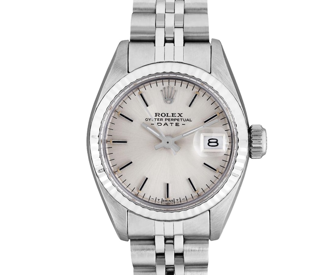 Rolex Ladies Stainless Steel 14K Fluted Bezel Date Watch: This Lady Rolex Date watch features a silver dial with index hour markers and a custom plastic crystal, with a magnified date window. The timepiece has Rolex 14K white gold fluted bezel. The Rolex 26m