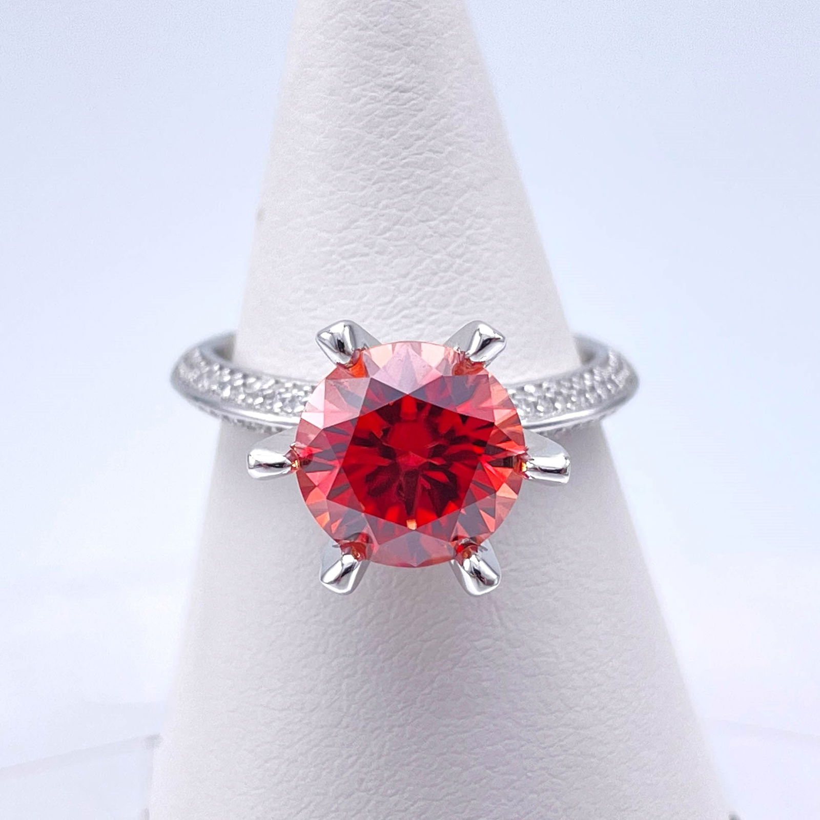 Dazzling 3 Ct VVs1 Simulated Padpaparacha Sapphire Ring: This Fine 3 Ct Lab Simulated Padpaparacha Sapphire Centerstone is a VVs1 Brilliant Round Cut Measuring 9 mm. It has a beautiful dark orange vivid red hue. This high-quality gem is near flawless and bu