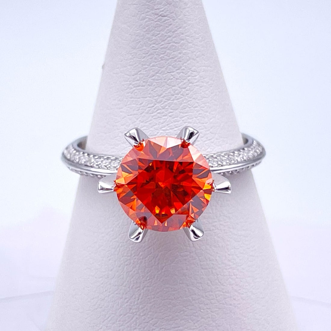 Plated 14KT White Gold 3 Ct VVs1 Bright Orange Moissanite Ring: This Fine 3 Ct Moissanite Centerstone is a VVS1 Brilliant Round Cut Measuring 9 mm. The Color a Vivid Bright Orange. This Fire Moissanite is near flawless and bursting out with a full spectrum of colo