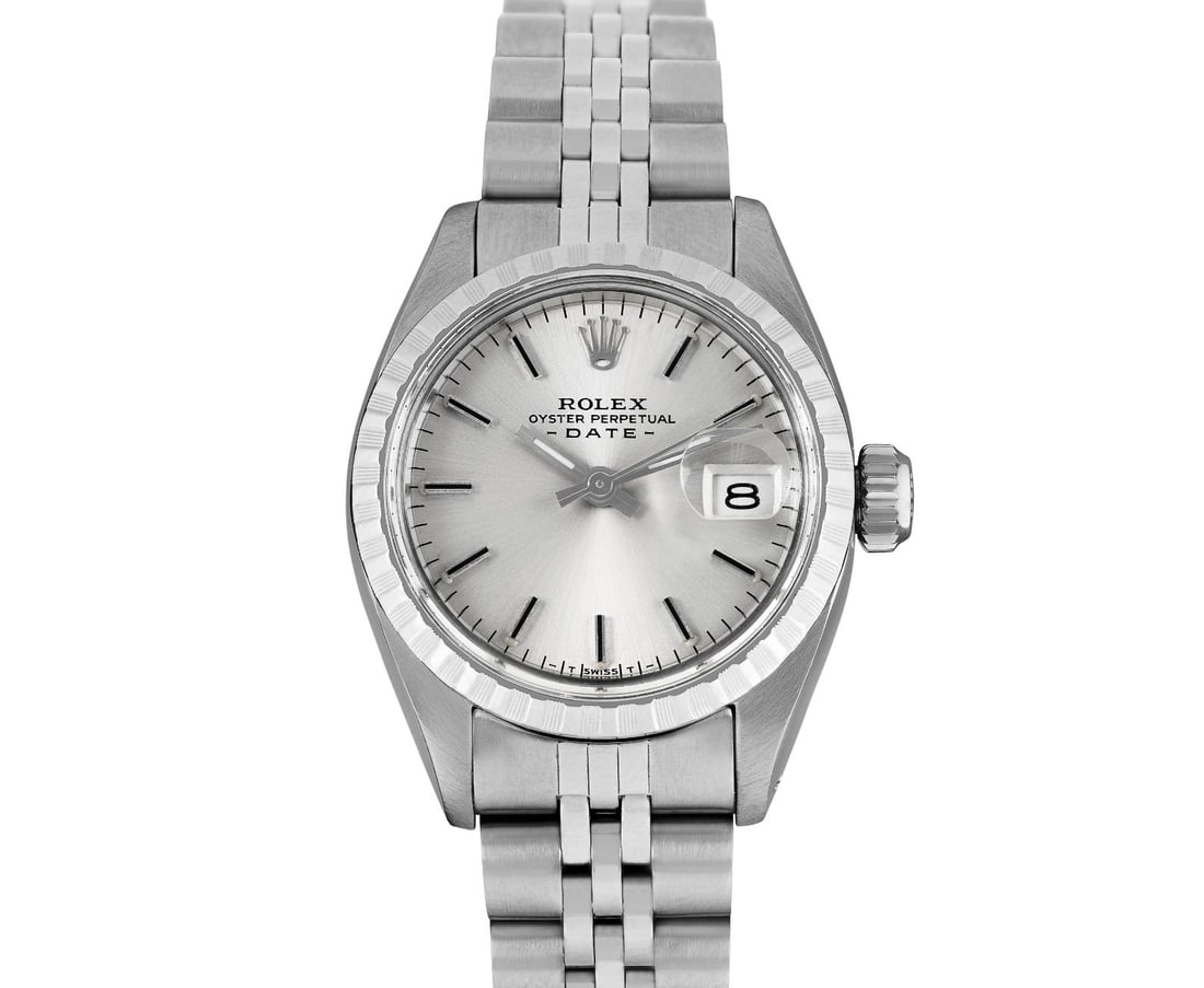 Rolex Ladies Stainless Steel Engine Turn Bezel Date Watch: This Lady Rolex Date watch features a silver dial with index hour markers and a custom plastic crystal, with a magnified date window. The timepiece has Rolex stainless steel engine turn bezel. The