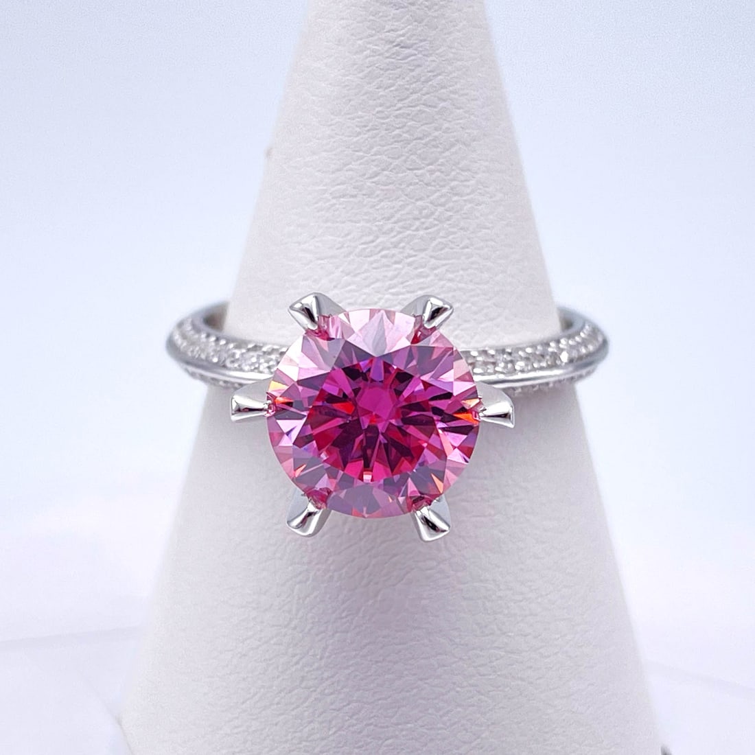 Plated 14KT White Gold 3 Ct VVs1 Dark Pink Fire Moissanite Ring: This Fine 3 Ct Moissanite Centerstone is a VVS1 Brilliant Round Cut Measure sing 9 mm. The Color a Vivid Dark Pink. This Fire Moissanite is near flawless and bursting out with a full spectrum of color