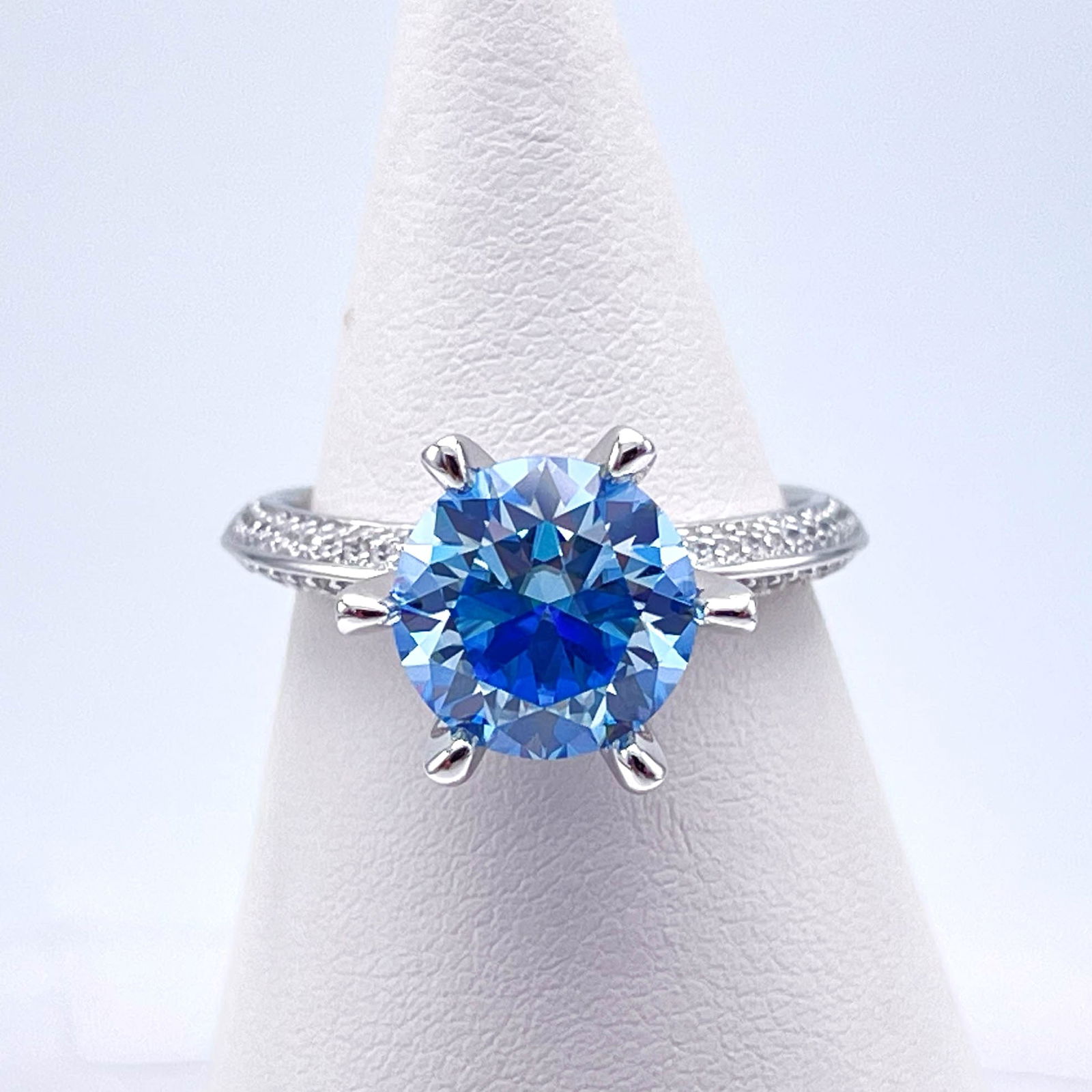 Plated 14KT White Gold 3 Ct VVs1 Cornflower Blue Moissanite Ring: This Fine 3 Ct Moissanite Centerstone is a VVS1 Brilliant Round Cut Measure sing 9 mm. The Color a Vivid Cornflower Blue. This Fire Moissanite is near flawless and bursting out with a full spectrum of