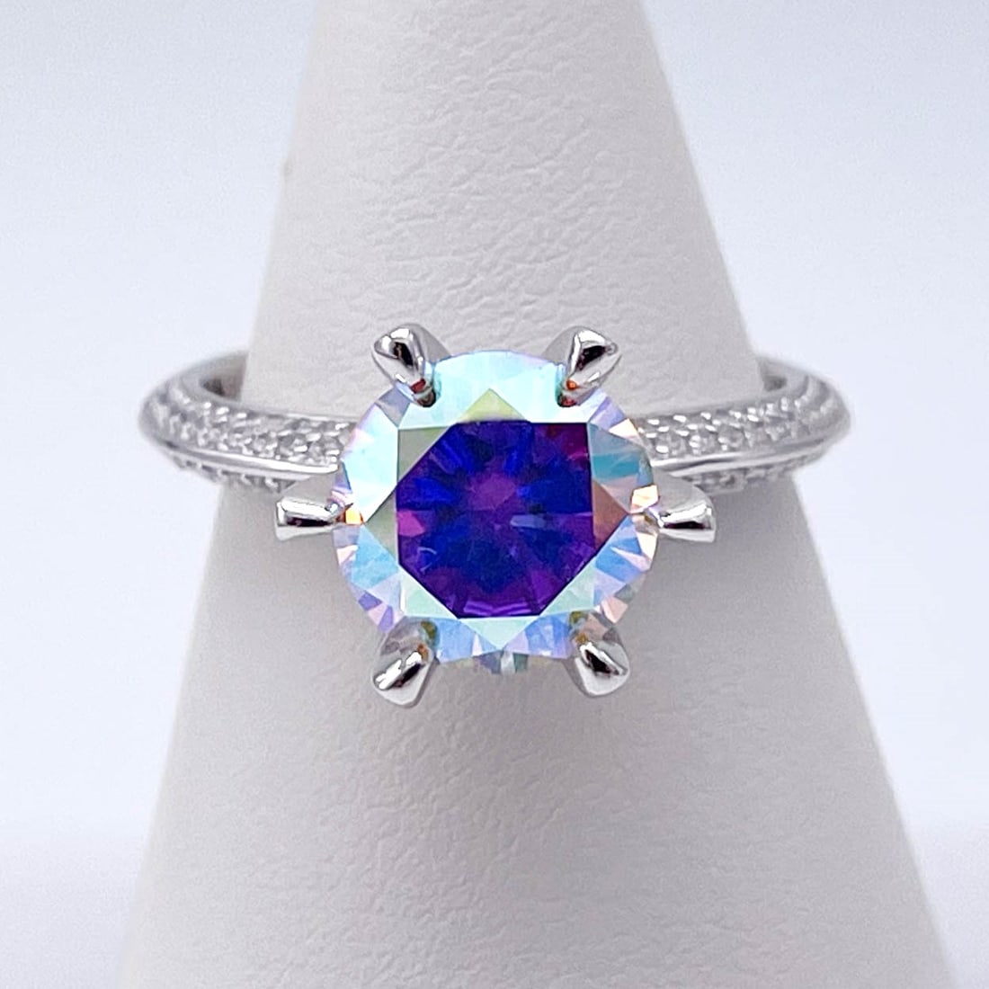 Plated 14KT White Gold 3 Ct VVs1 Rainbow Fire Moissanite Ring: This Fine 3 Ct Rainbow Fire Moissanite Centerstone is a VVS1 Brilliant Round Cut Measuring 9 mm. It has multiple flashes of color including, but not limited to orange, pinks, golds and bright white. T