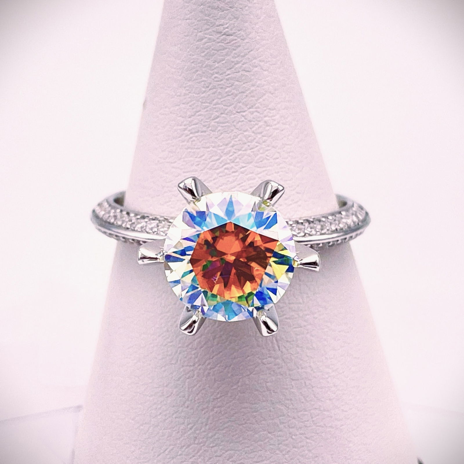 Plated 14KT White Gold 3 Ct VVs1 Rainbow Fire Moissanite Ring: This Fine 3 Ct Rainbow Fire Moissanite Centerstone is a VVS1 Brilliant Round Cut Measuring 9 mm. It has multiple flashes of color including, but not limited to orange, pinks, golds and bright white. T