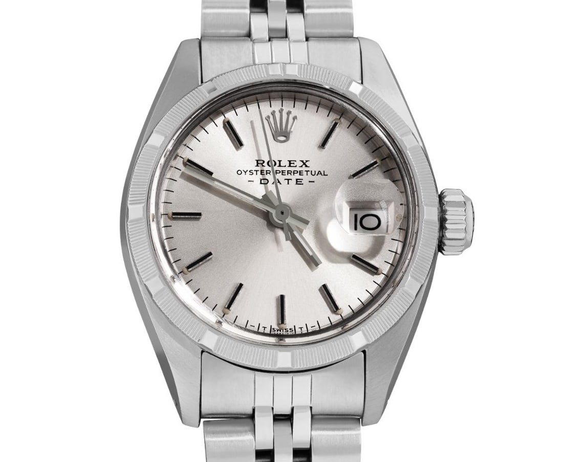 Rolex Ladies Stainless Steel 26MM Date Watch: This Lady Rolex Date watch features a silver dial with index hour markers and a custom plastic crystal, with a magnified date window. The timepiece has Rolex stainless steel engine turn bezel. The Rol