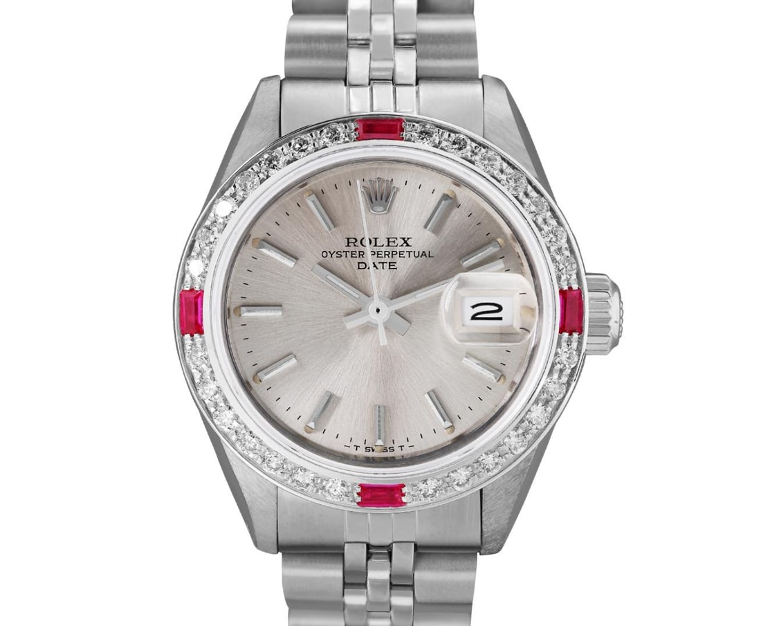 Rolex Ladies Stainless Steel Ruby And Diamond Bezel Date Watch: This Lady Rolex Date watch features a silver dial with index hour markers and a custom sapphire crystal, with a magnified date window. The timepiece has custom 18K white gold diamond and ruby bezel,