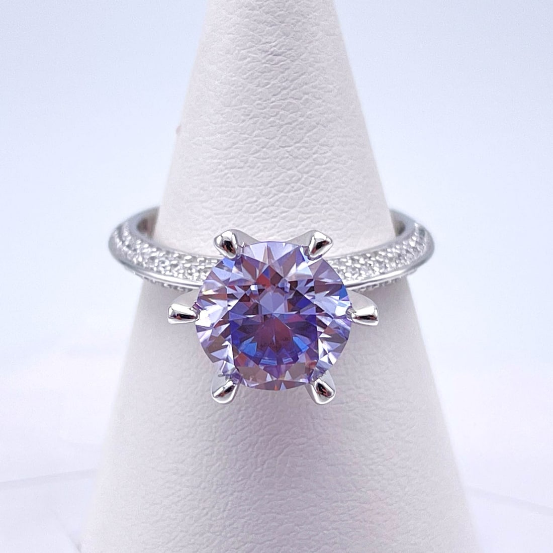 Plated 14KT White Gold 3 Ct VVs1 Blue Lilac Moissanite Ring: This Fine 3 Ct Moissanite Centerstone is a VVS1 Brilliant Round Cut Measure sing 9 mm. It has a full even vivid Blue Lilac Hue. This Fire Moissanite is near flawless and bursting out with a full