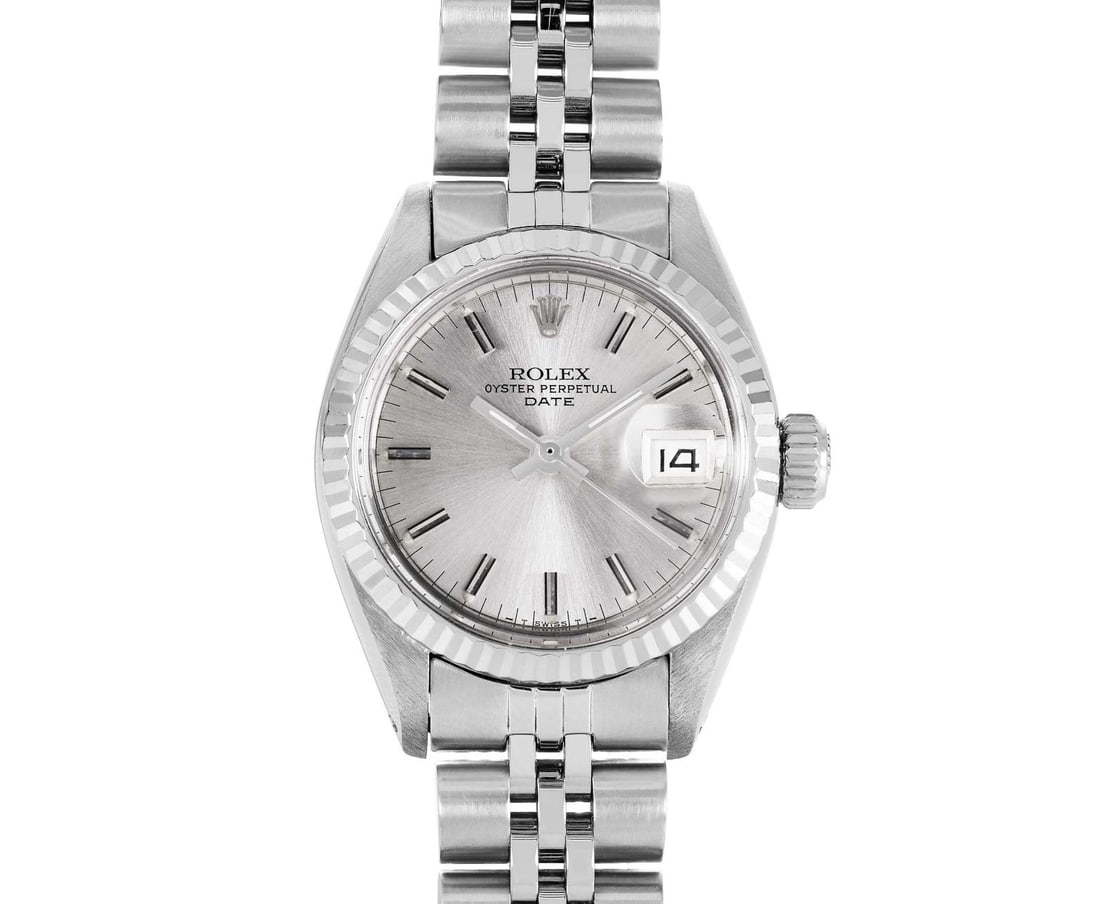 Rolex Ladies Stainless Steel 14K Fluted Bezel Date Watch: This Lady Rolex Date watch features a silver dial with index hour markers and a custom plastic crystal, with a magnified date window. The timepiece has Rolex 14K white gold fluted bezel. The Rolex 26m