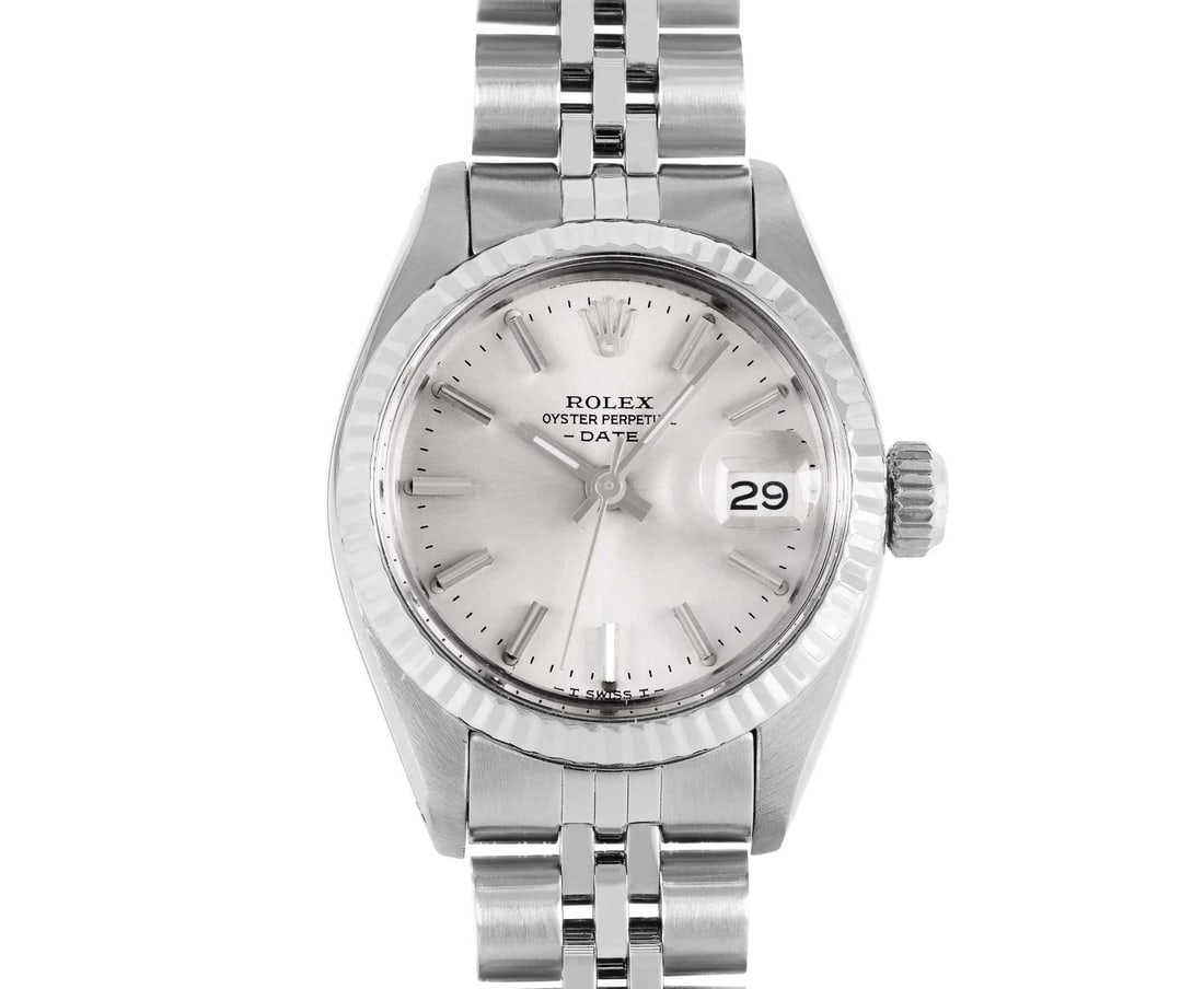Rolex Ladies Stainless Steel 14K Fluted Bezel Date Watch: This Lady Rolex Date watch features a silver dial with index hour markers and a custom plastic crystal, with a magnified date window. The timepiece has Rolex 14K white gold fluted bezel. The Rolex 26m