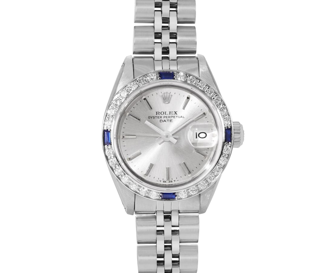 Rolex Ladies Stainless Steel Sapphire And Diamond Bezel Date Watch: This Lady Rolex Date watch features a silver dial with index hour markers and a custom sapphire crystal, with a magnified date window. The timepiece has custom 18K white gold diamond and sapphire beze