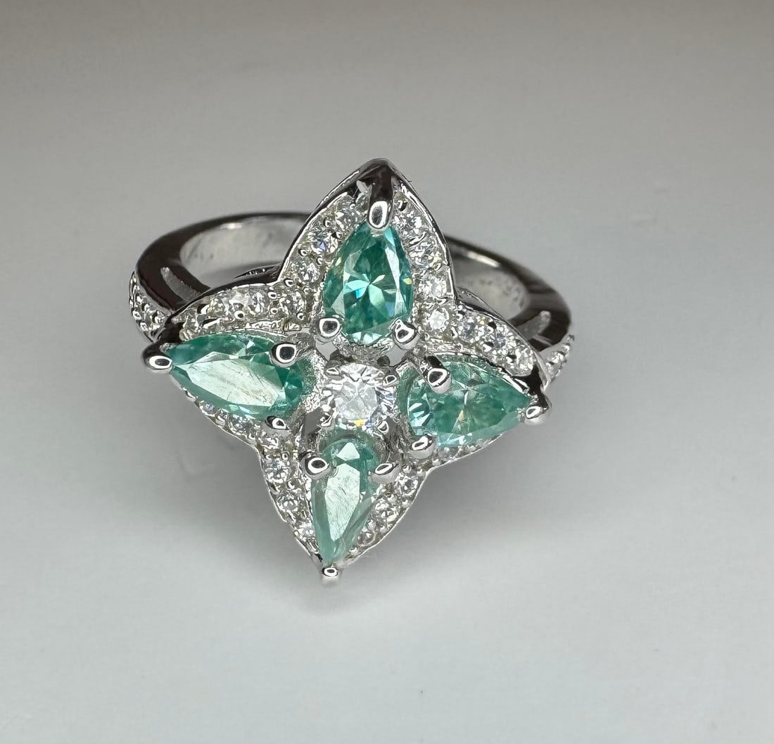 Dazzling 3.75 Ct Green Fire Moissanite Ring: 3.75 Ct Mint Green Moissanite Ring. This Moissanite gemstone has four pear cuts with cz accent stones. Mounted in solid .925 sterling silver complimented by rhodium which is a precious metal that is