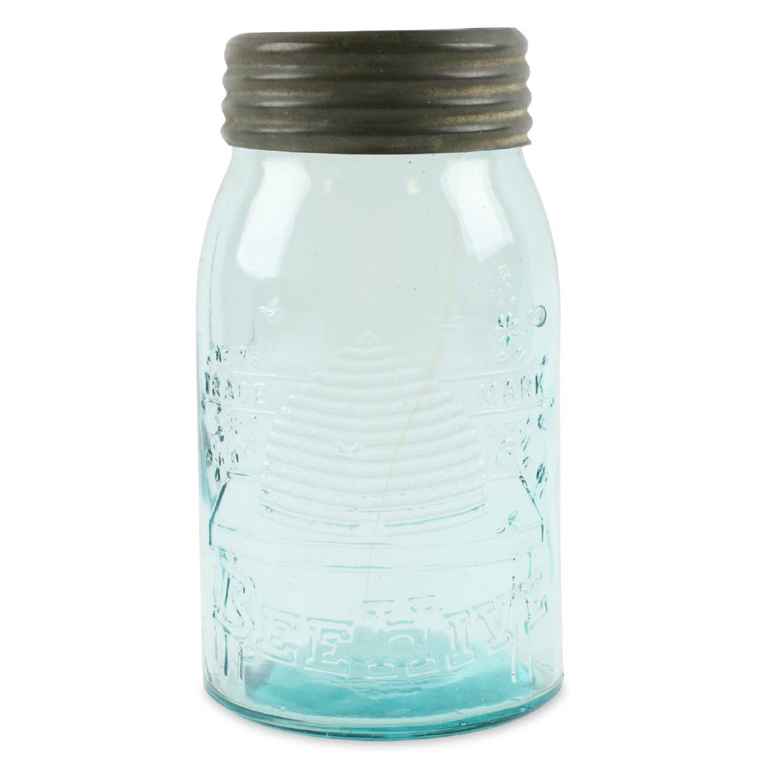 Aqua Beehive Quart Fruit Jar: American quart, five bees. Aqua lid with small cross center. Zinc band. Faint amber strings of colour front and back. Intact bubble top right of front design. Condition: Excellent. Fleck on lower and