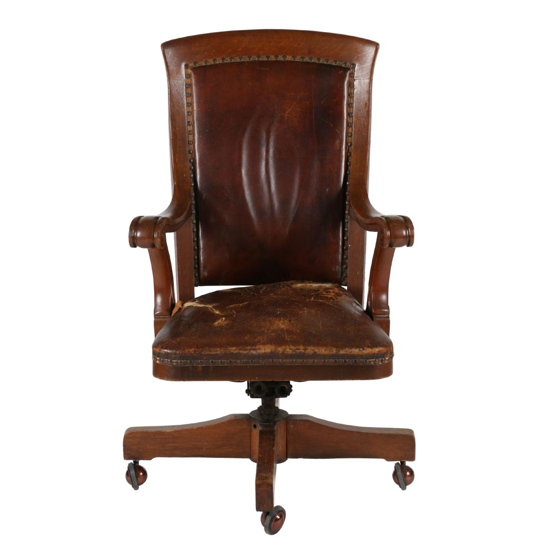 Victorian Oak Swivel Chair: C.1900. Victorian. Quarter-sawn oak. Ornately carved arm rests. 27" x 45” x 24”. Fair. Original leather seat cover requires re-upholstering. 200-300