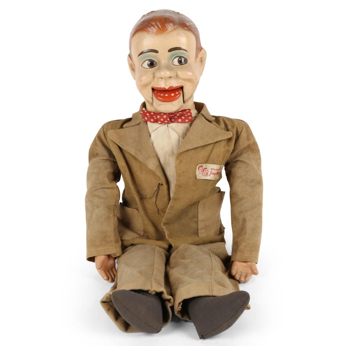 Jerry Mahoney Ventriloquist Doll: Clothed in original outfit including bow tie. Tag reads "Paul Winchell's Jerry Mahoney." 23" x 9" x 4". Staining and soil to costume. Retains original composite hands. Crazing to hands and face. Minor