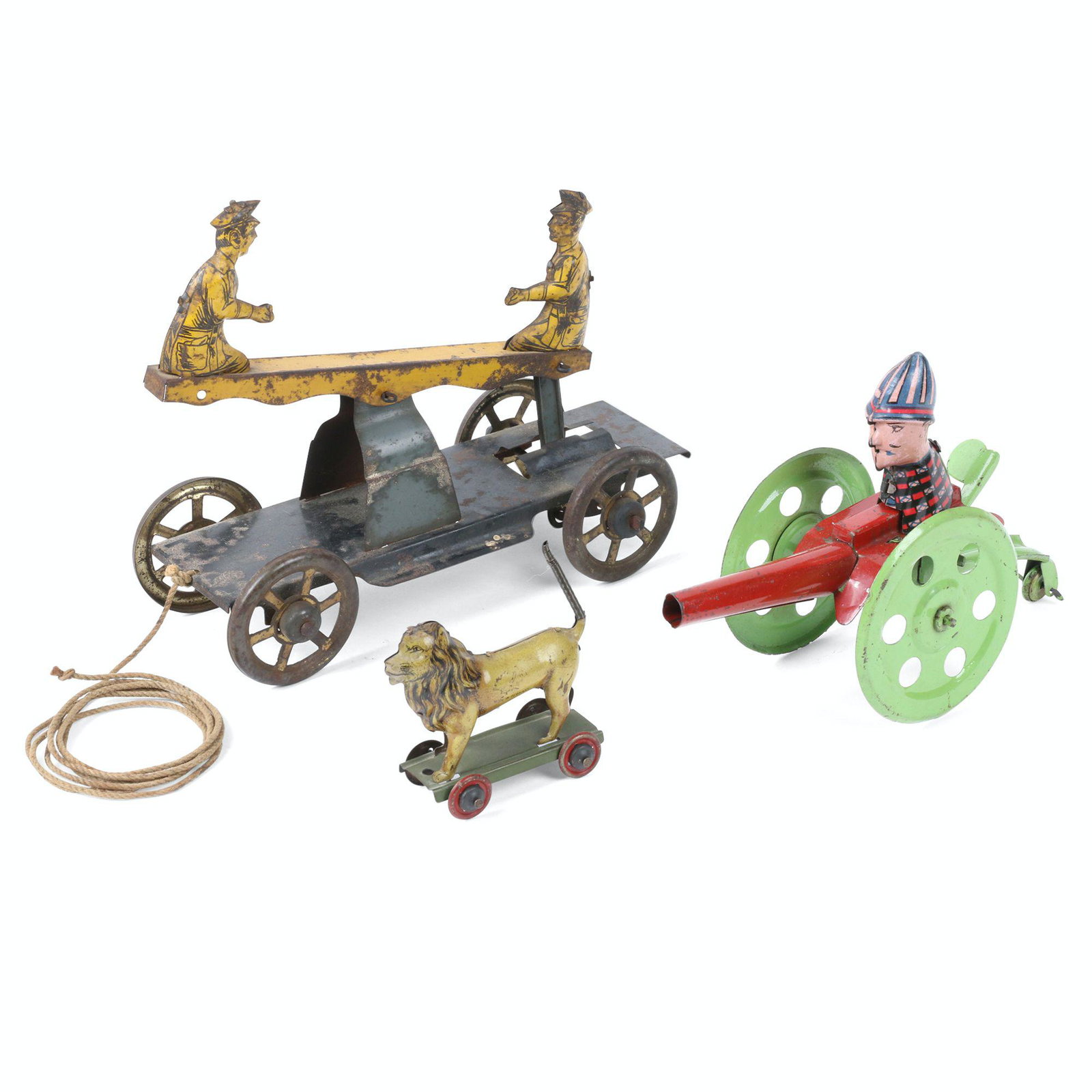 German Tin Litho Toys: Three (3). German. 2.5" to 7.5" (l). Lion marked, "Made in Germany". Cannon toy action functioning. Includes Converse Teeter-Totter Pull Toy, Lion penny toy and German tin rolling cannon. Teeter-Totte