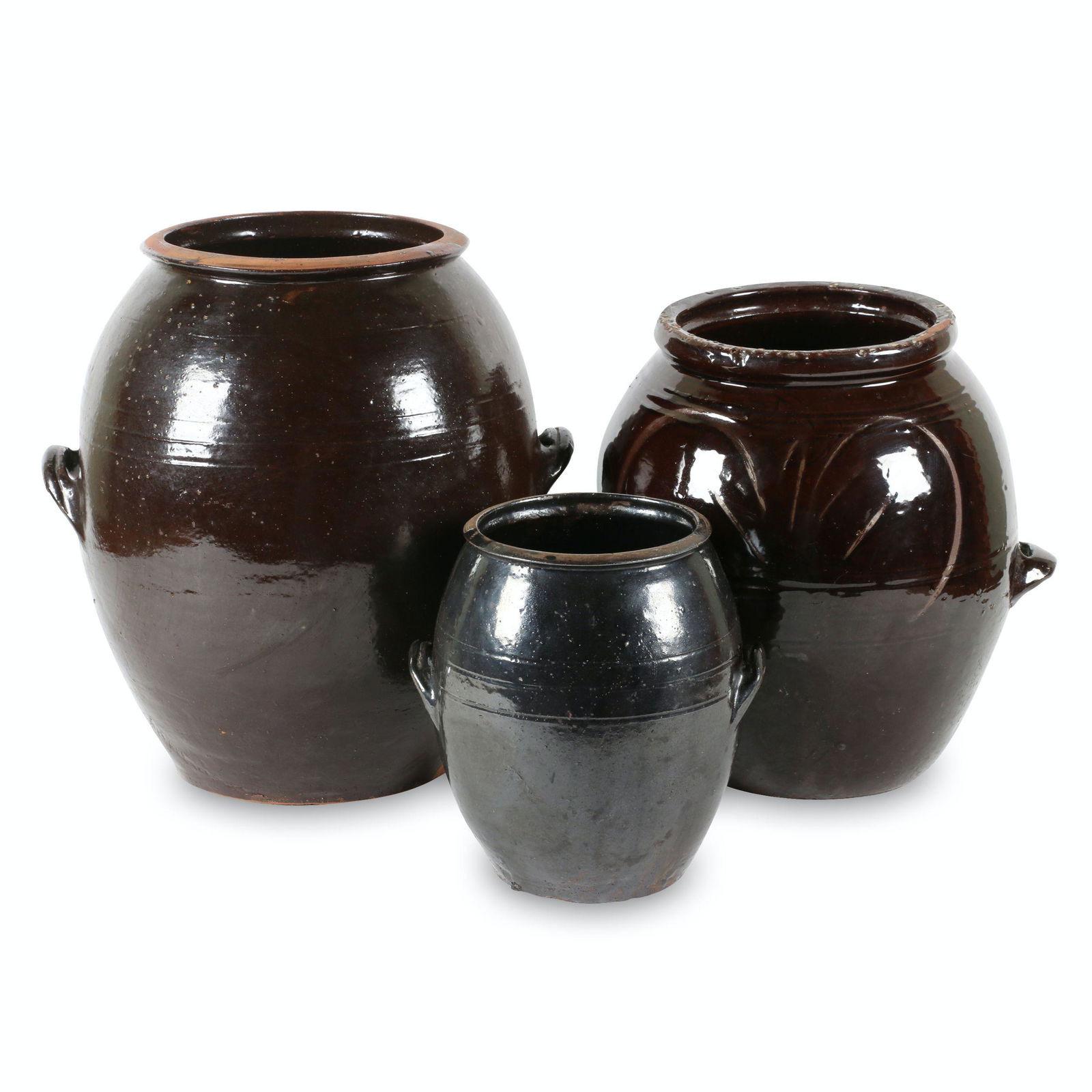 Early Redware Crocks: Three (3). Canadian. Earthenware. Each covered in brown albany slip glaze. Ovoid forms. Mid-size jar features in-glaze decoration. 9" to 15" (h). Largest noted, "GUELPH", mid size noted, "BARRIE", sma