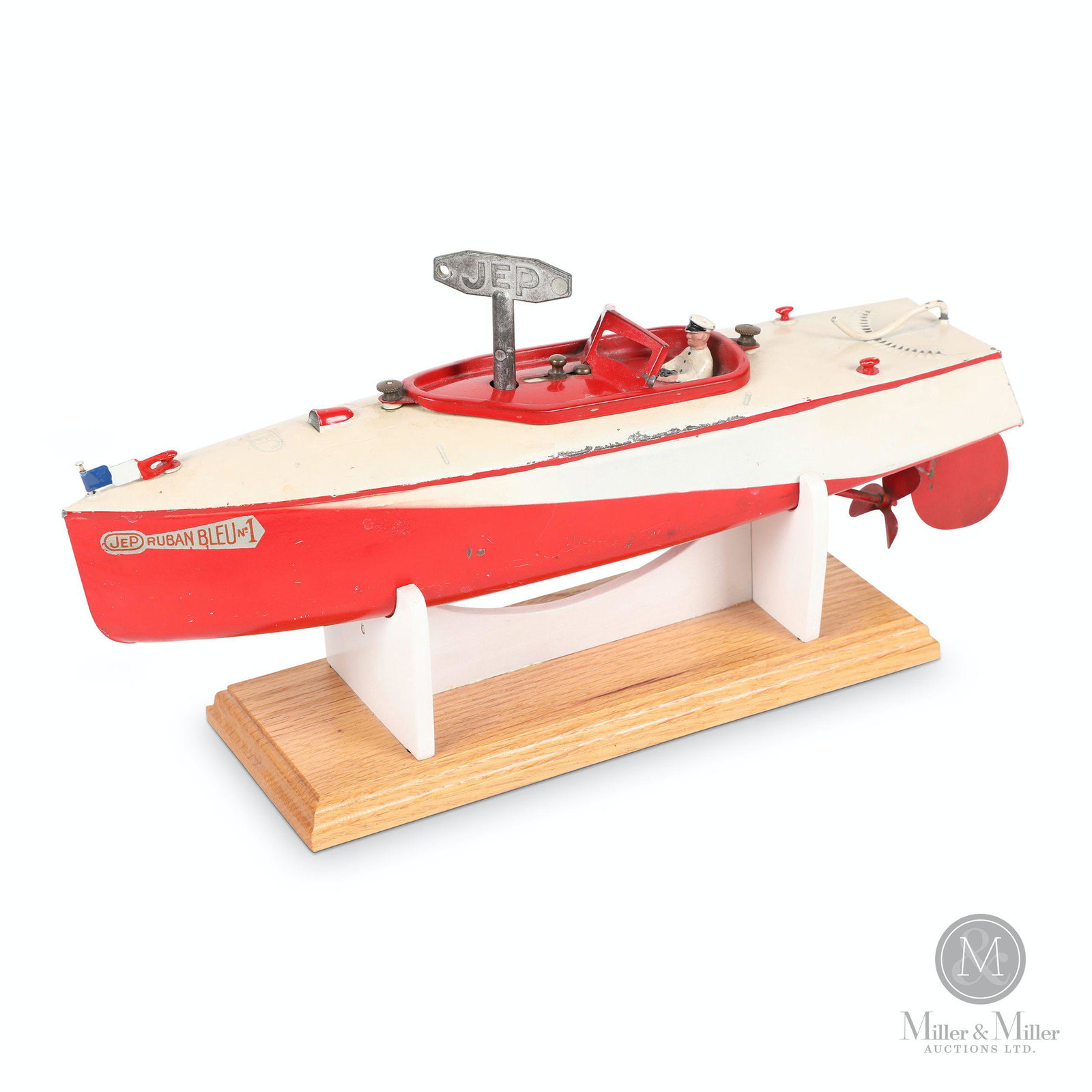 JEP Ruben Bleu No. 1 Boat Toy: French. 1930s. Pressed steel. Clockwork motor. Includes contemporary display stand. Decalled, "JEP Ruban Bleu No. 1". Embossed, "Unis France JEP". 13.5 x 3 x 4.5". Mechanically functioning. Exhibits m
