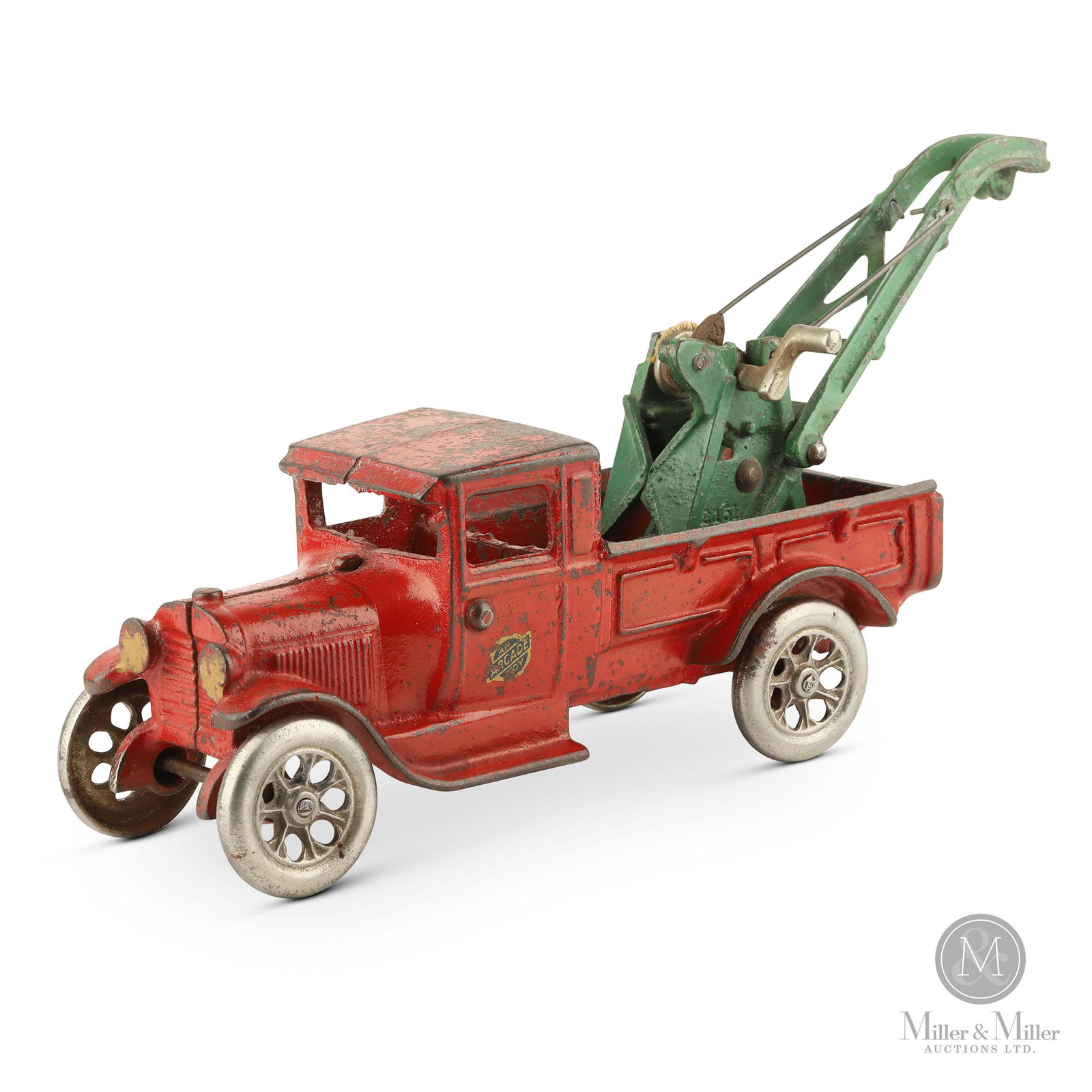 Cast Iron Tow Truck by Arcade: An Arcade tow truck toy in red paint with a green tow bar and nickel plated wheels and winch. Original decal, although showing some loss, still intact on driver's door. Worn paint, good condition over