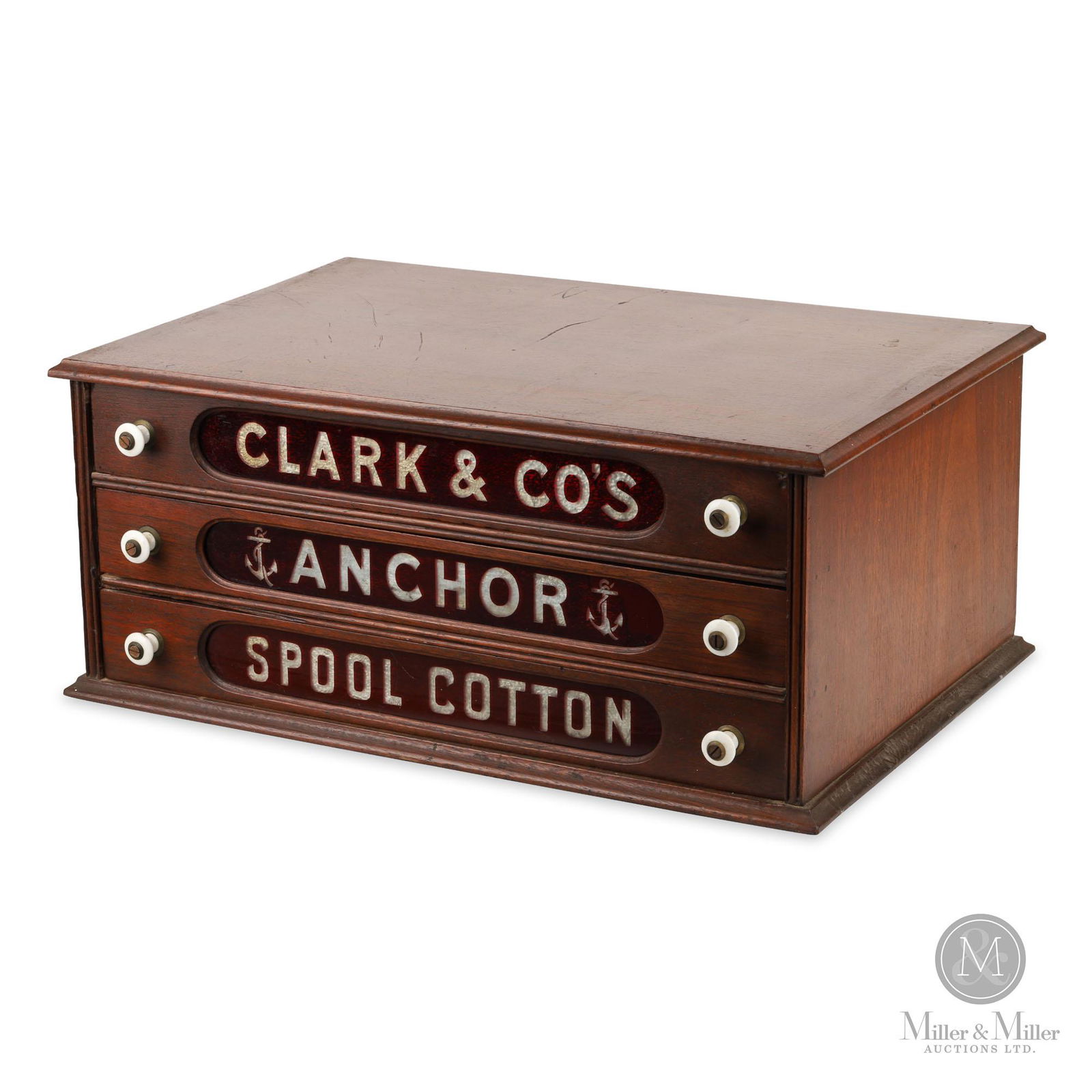 Clark & Co. Anchor Spool Cotton Cabinet: American. 1890s. Walnut with ruby cut-to-clear glass drawer panels and porcelain knobs. The glass panel in the lowest drawer exhibits a tight horizontal crack near the center. Features velvet-lined dr