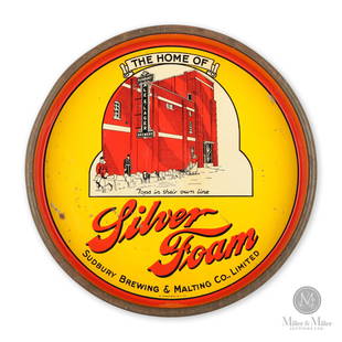 Sudbury Brewing Silver Foam Beer Tray: Sudbury, Ontario. 1940s. Tin lithograph. Features the Sudbury Brewing factory behind a Northern dogsled team with the script, "Tops in their own line". Signed lower edge, "St Thomas Metal Signs Ltd".