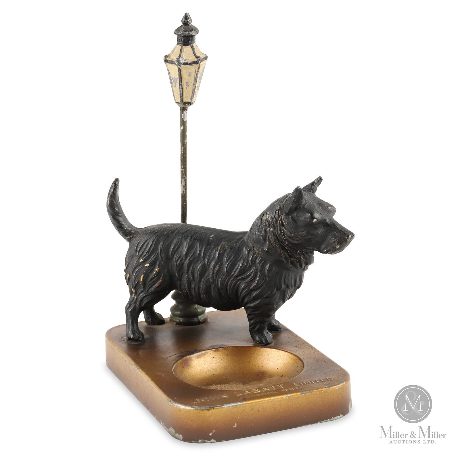 John Labatt Scottie Paper Clip Holder: 1920s. Spelter and pressed steel. Features a Scottish Terrier standing proudly next to a street lamp. Embossed "John Labatt Limited" and stamped underneath, "Made in Germany". Very minor surface losse